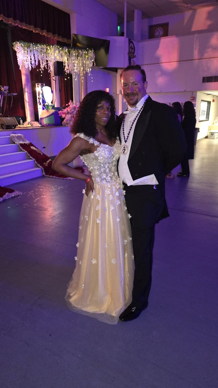 Robert and Andrea Myrick attending a formal event, dancing with colorful lighting and decorated stage in the background.