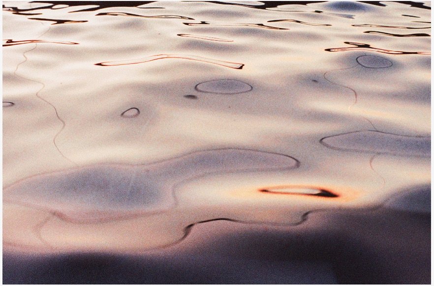 Calm water with gentle ripples and reflections of the sky during sunset.