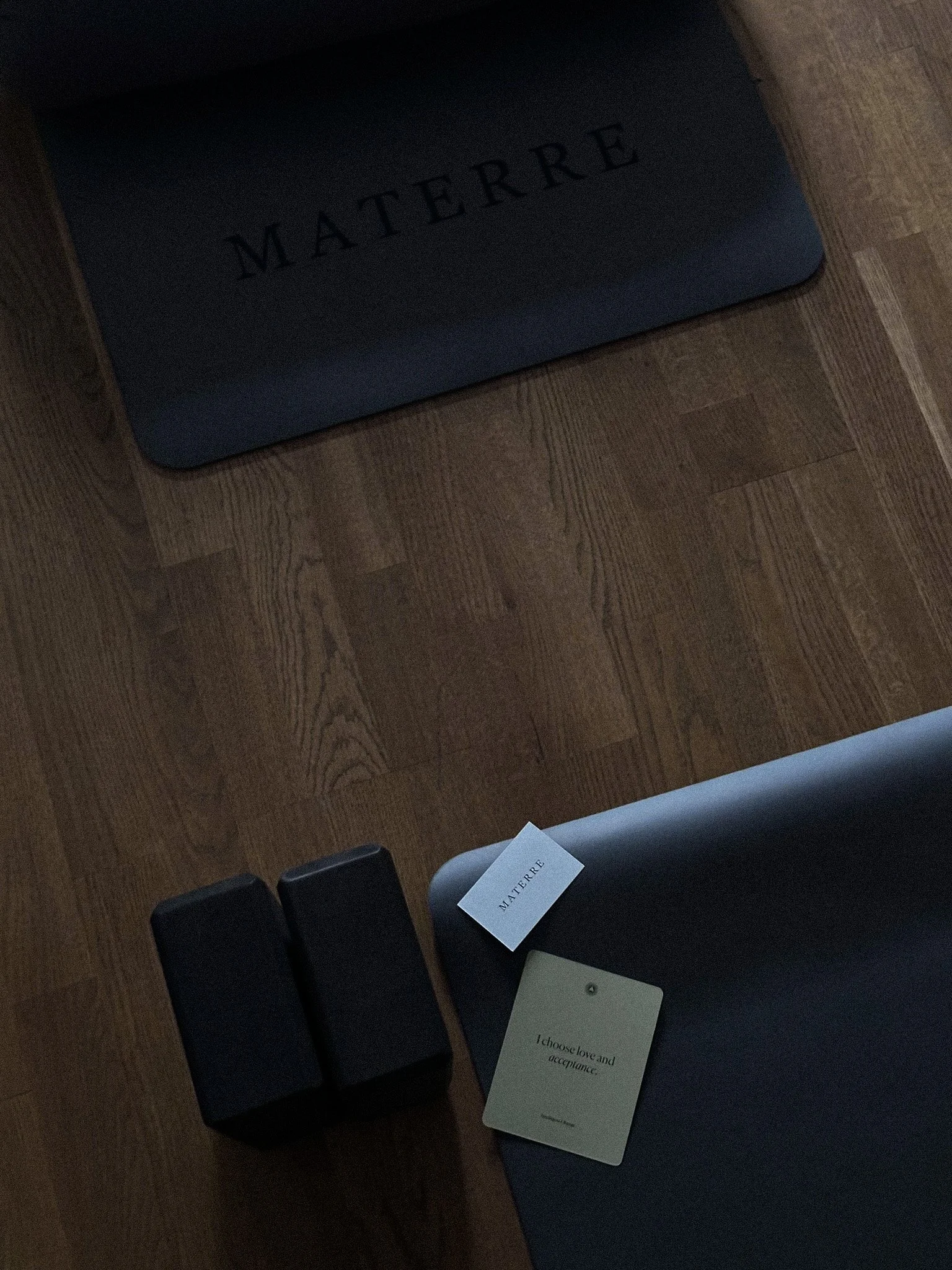 A photo of a dark wooden table with black chairs around it, a dark-colored box with 'MATIÈRE' written on it, and two cards with the word 'I choose love and acceptance.'