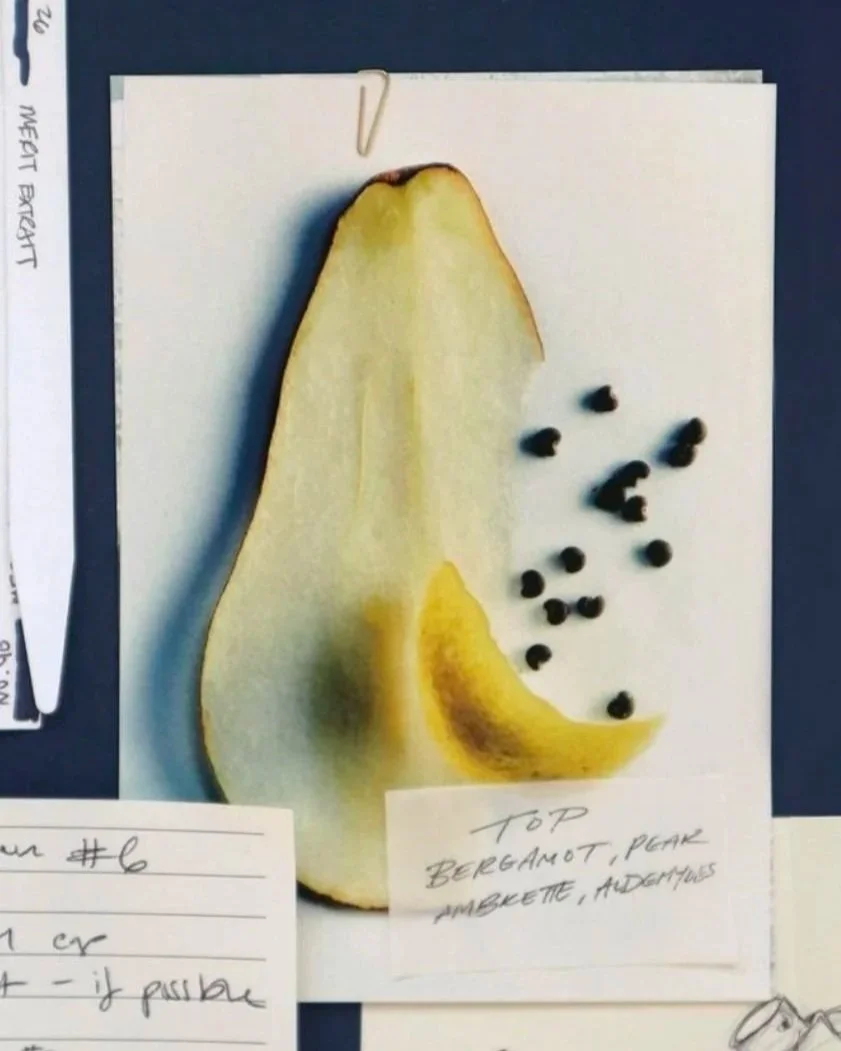 A sliced pear with black peppercorns on white paper in a kitchen or dining setting.