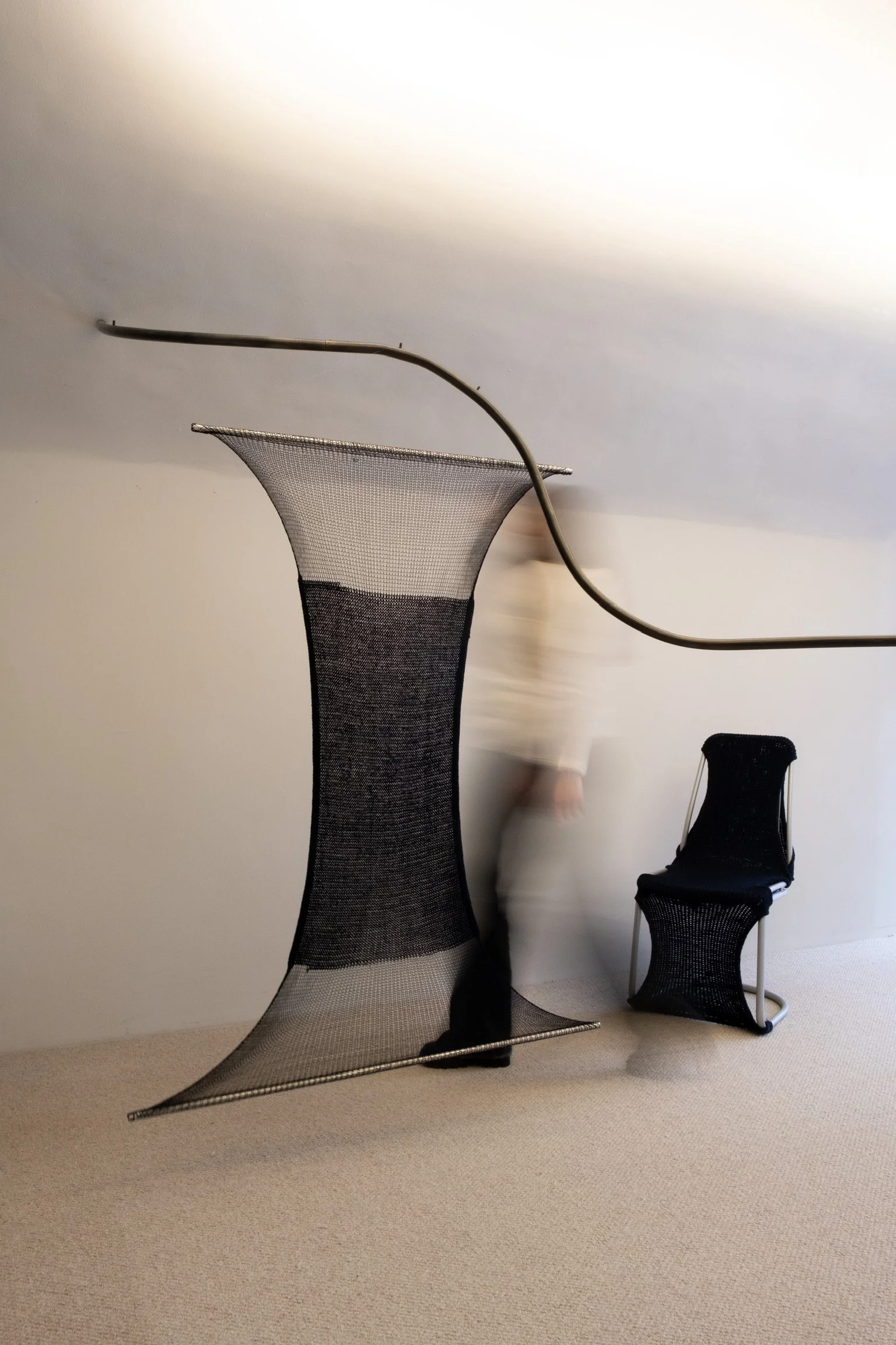 Woven sculptural textile pieces displayed in a minimal interior space
