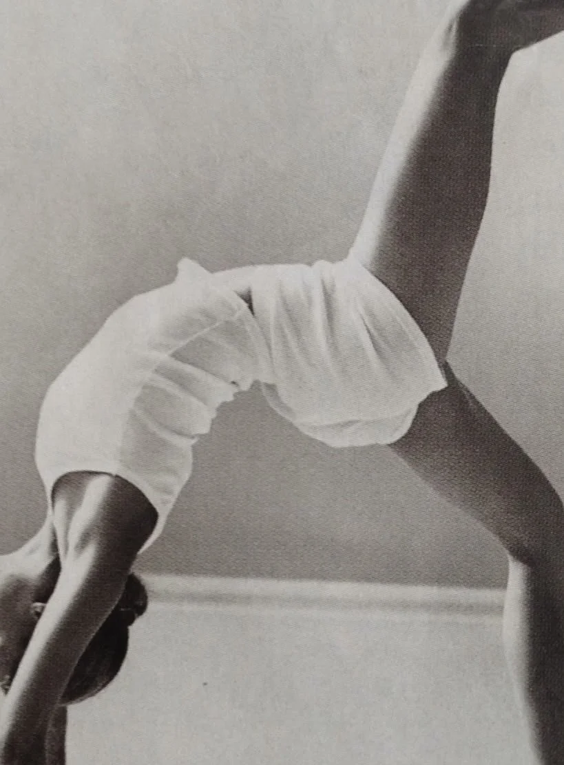 A young girl in a white dress in a yoga pose, with her hands and feet on the ground and her back arched.