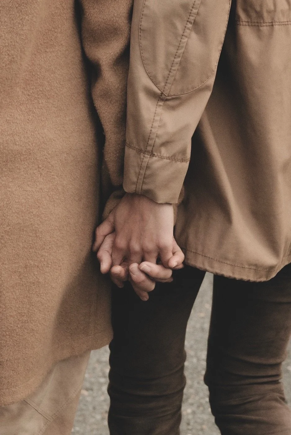 Two people holding hands while wearing neutral-toned clothes