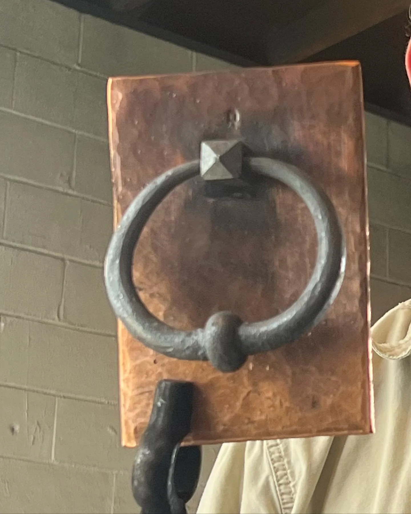 Custom door knocker, forged by hand atop a heavy copper base.