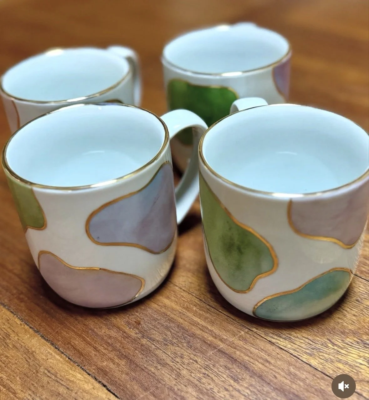 Quatro xícaras de chá decoradas com detalhes dourados, colocadas sobre uma mesa de madeira.