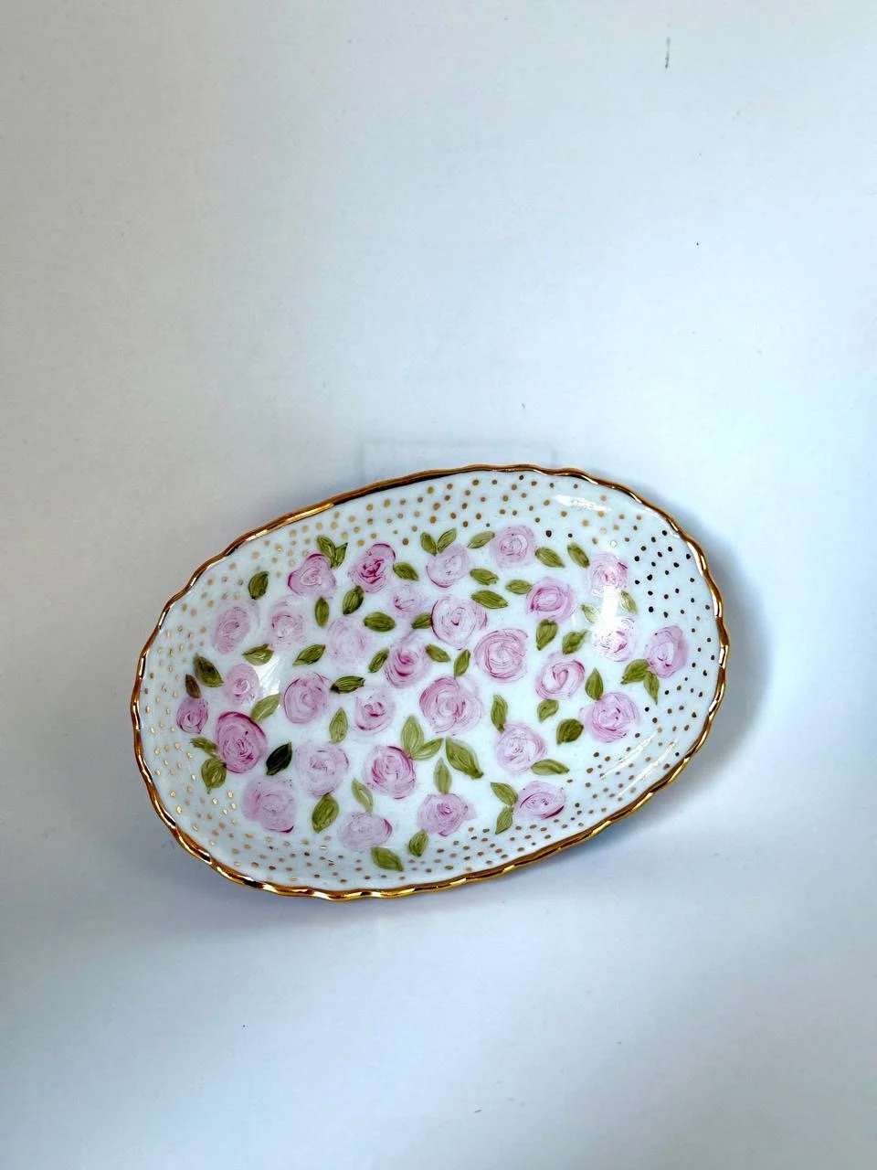 Bandeja ovalada decorada com flores rosa e folhas verdes, com borda dourada