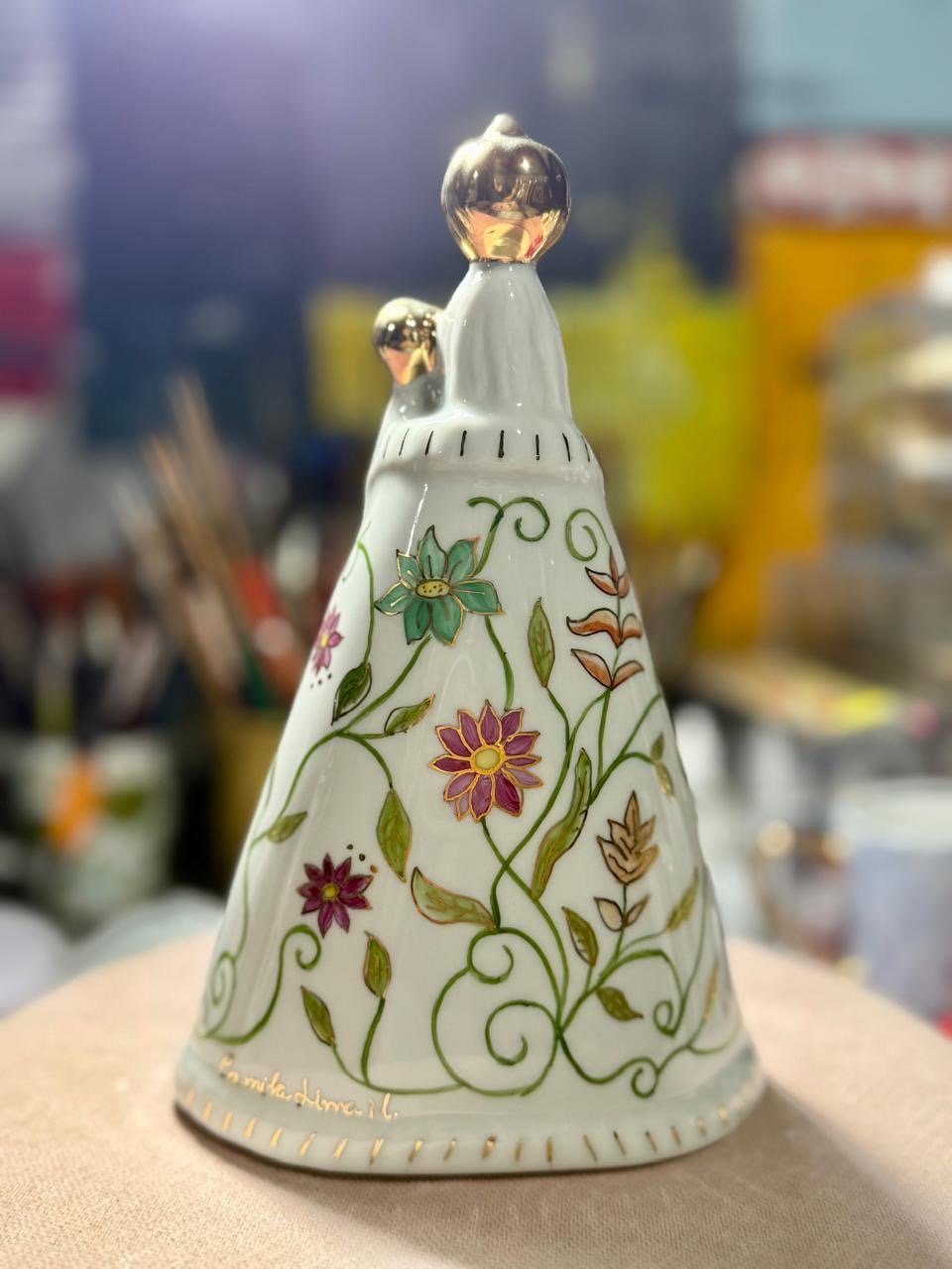 Estatueta de porcelana em forma de vestido com detalhes florais e detalhes dourados, com topo dourado.