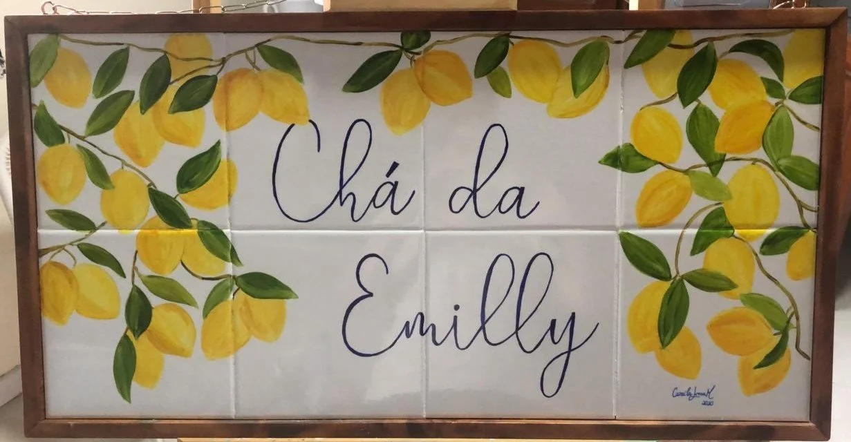 Tabuleiro de azulejos com pintura de ramos de limões e folhas verdes, com a frase "Chá da Emily" escrita ao centro em letras cursivas.