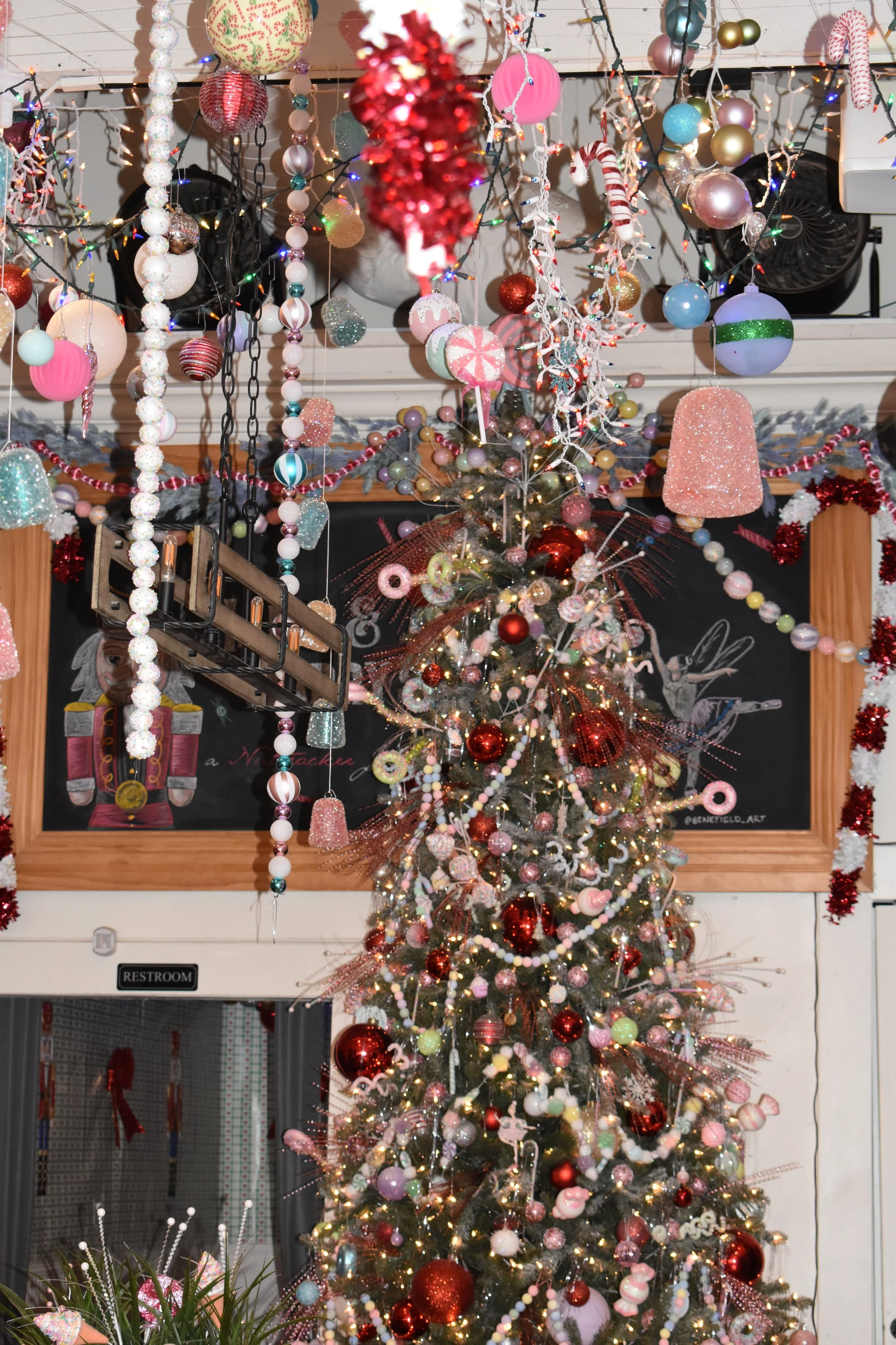 A festive Christmas decor with a decorated Christmas tree, hanging colorful ornaments, candy canes, and string lights in a cozy indoor setting.