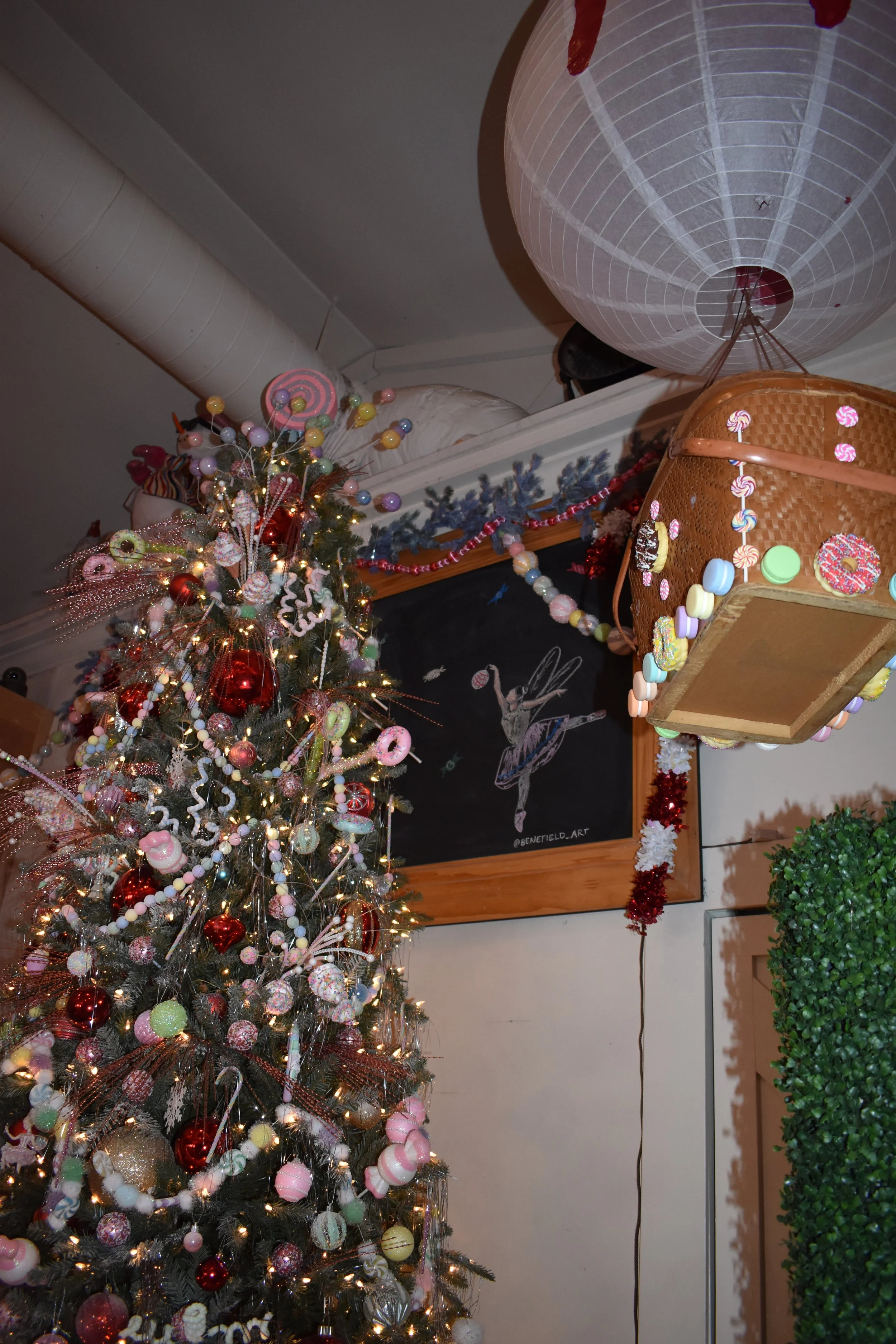Decorated Christmas tree with pink, red, and pastel ornaments, and a large paper lantern hanging from the ceiling.