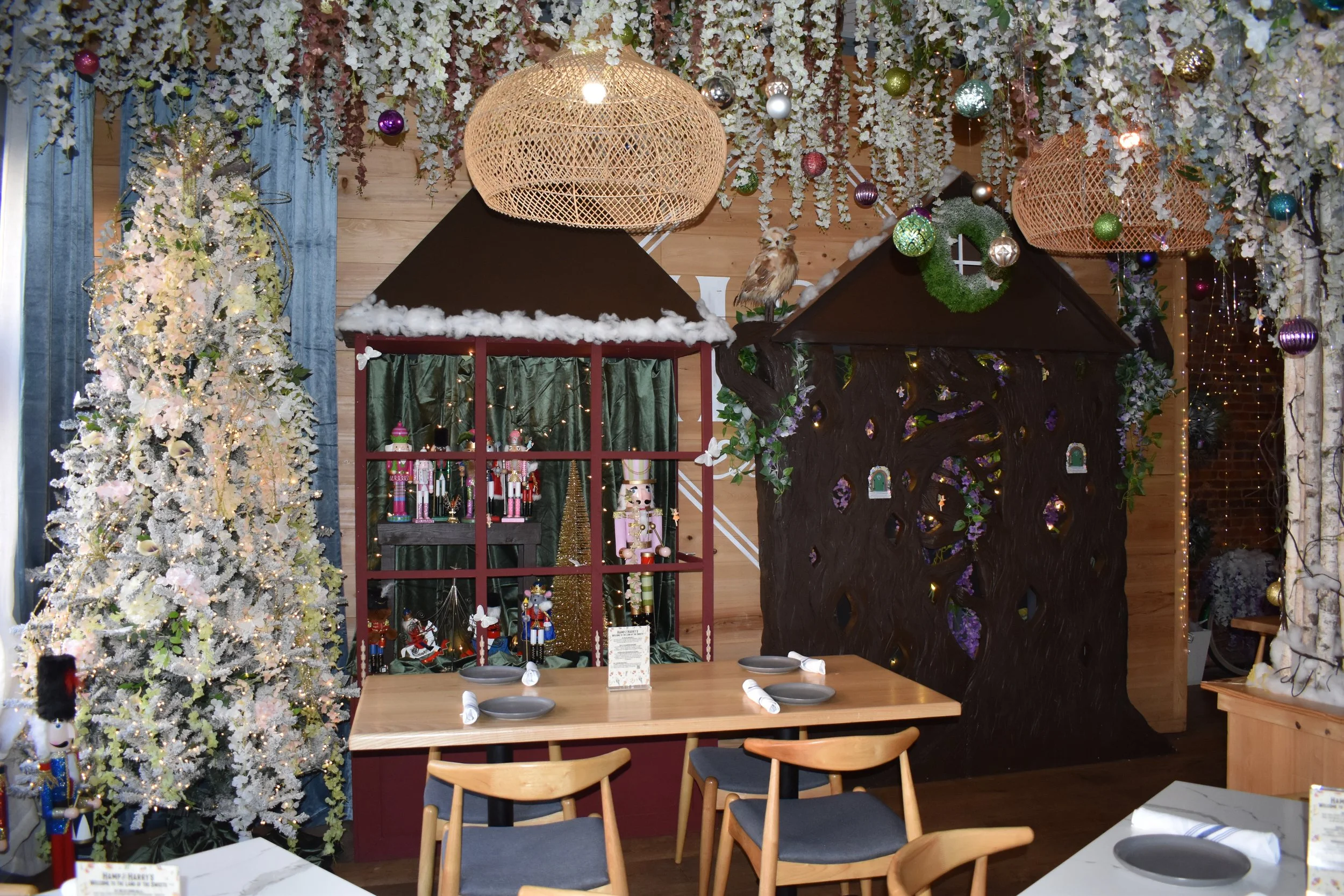A decorated Christmas-themed indoor scene with a white Christmas tree, a display of nutcracker figurines, and other holiday decorations, including ornaments and hanging lights.