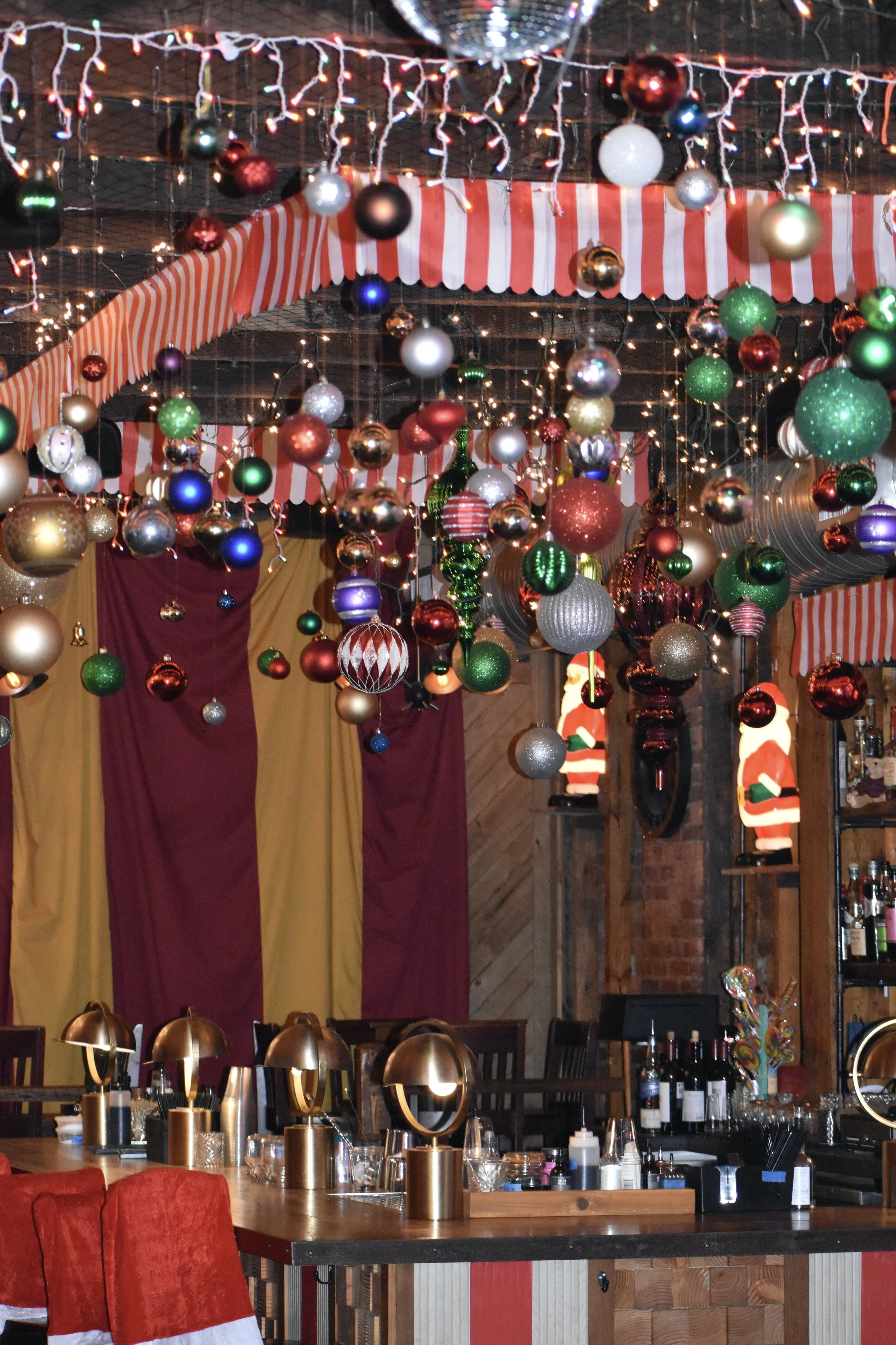 Indoor Christmas party with hanging ornaments, string lights, and Santa Claus decorations on the wall.