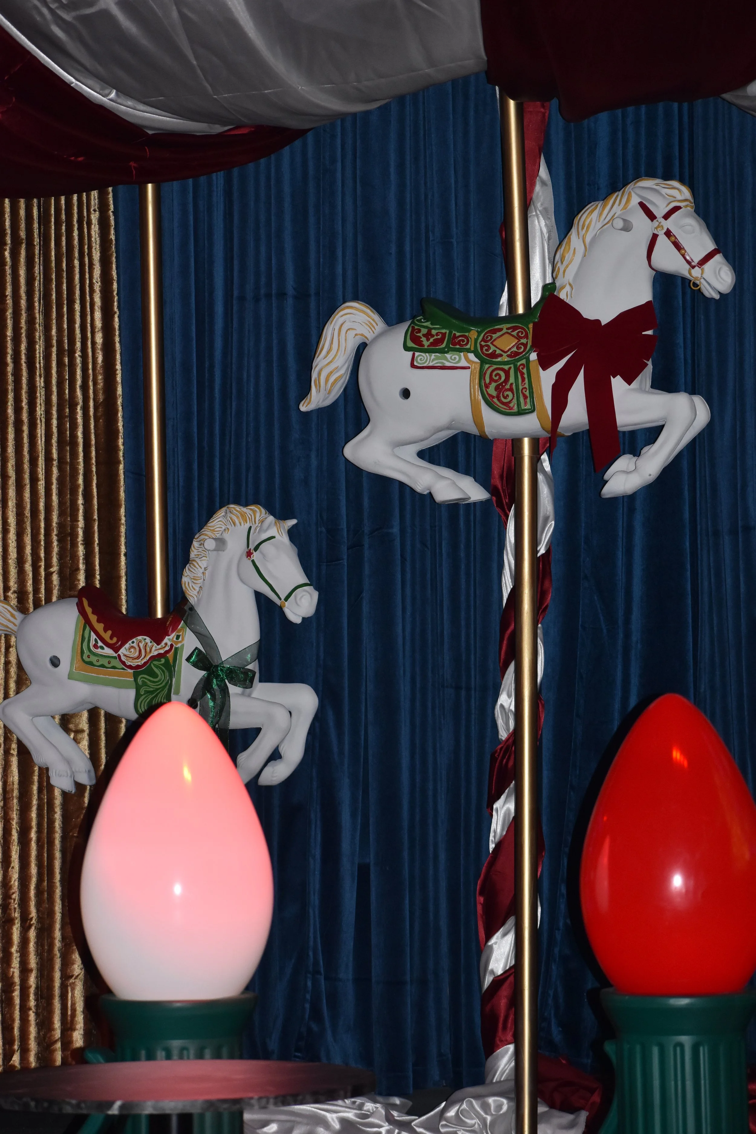 Decorative carousel horses and large Christmas egg ornaments on display.