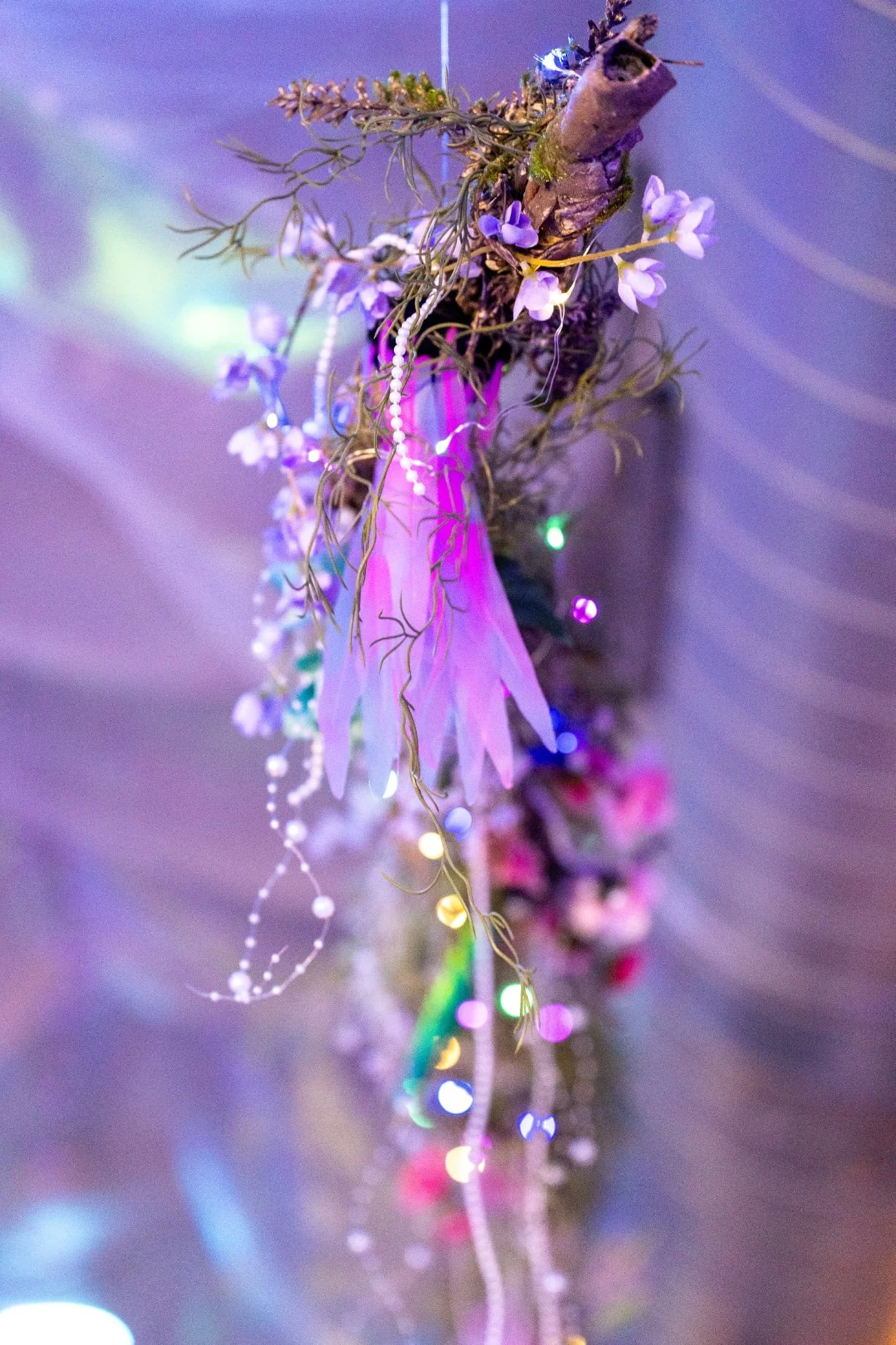 Close-up of a decorative hanging ornament made of dried flowers and branches, with colorful LED string lights.