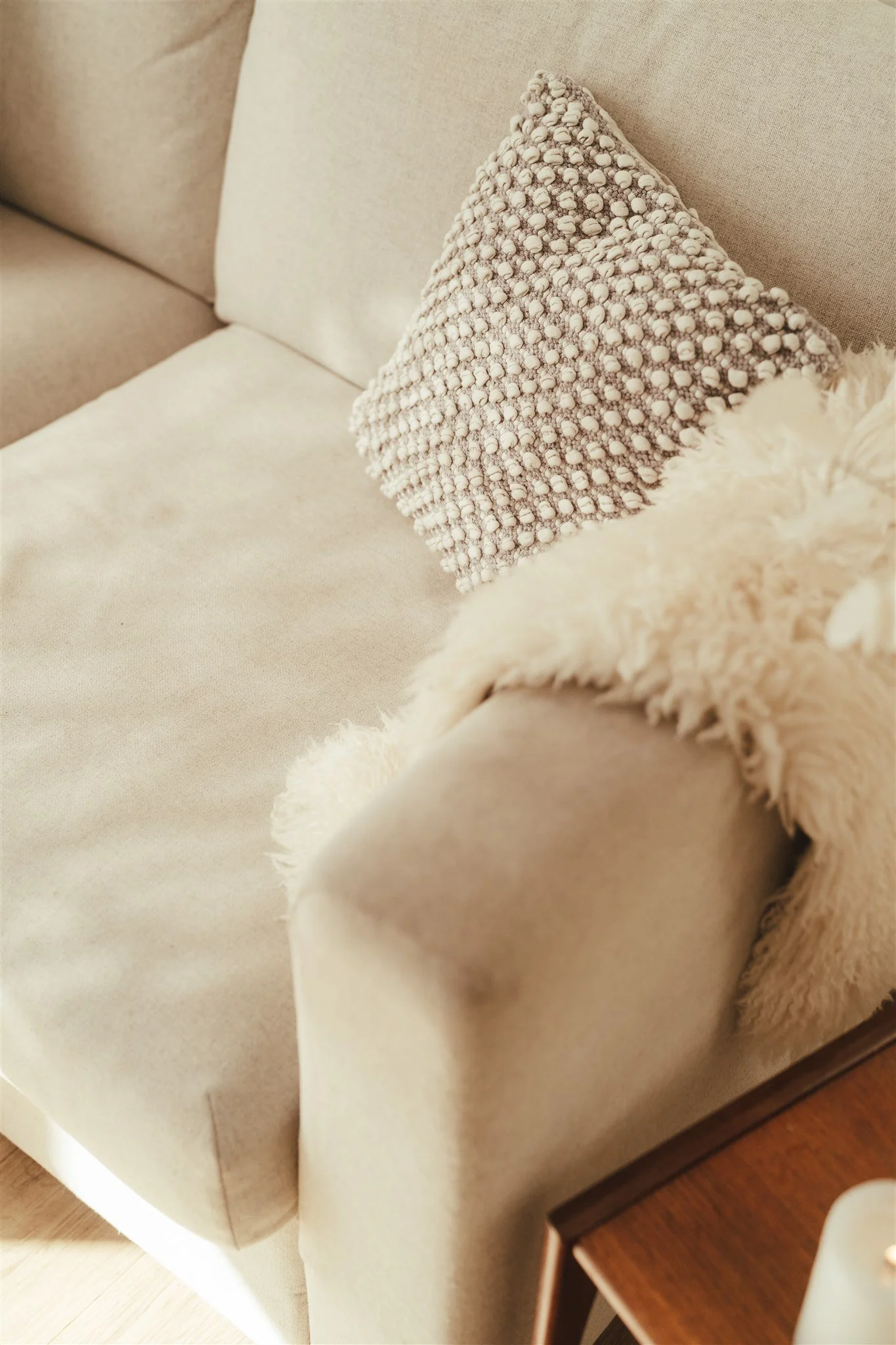 Cream-colored sofa with a textured throw pillow for decoration.