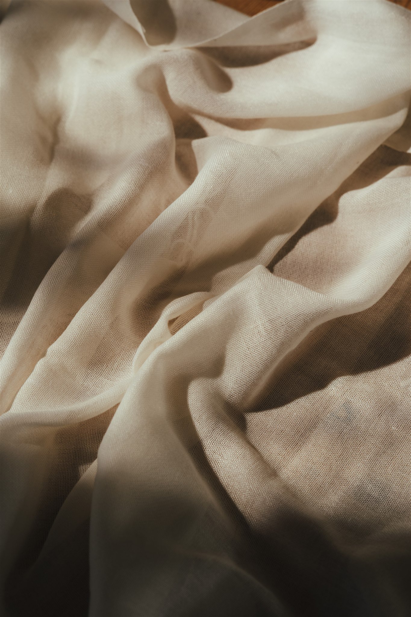 Close-up of beige fabric with soft folds and a slight sheen.
