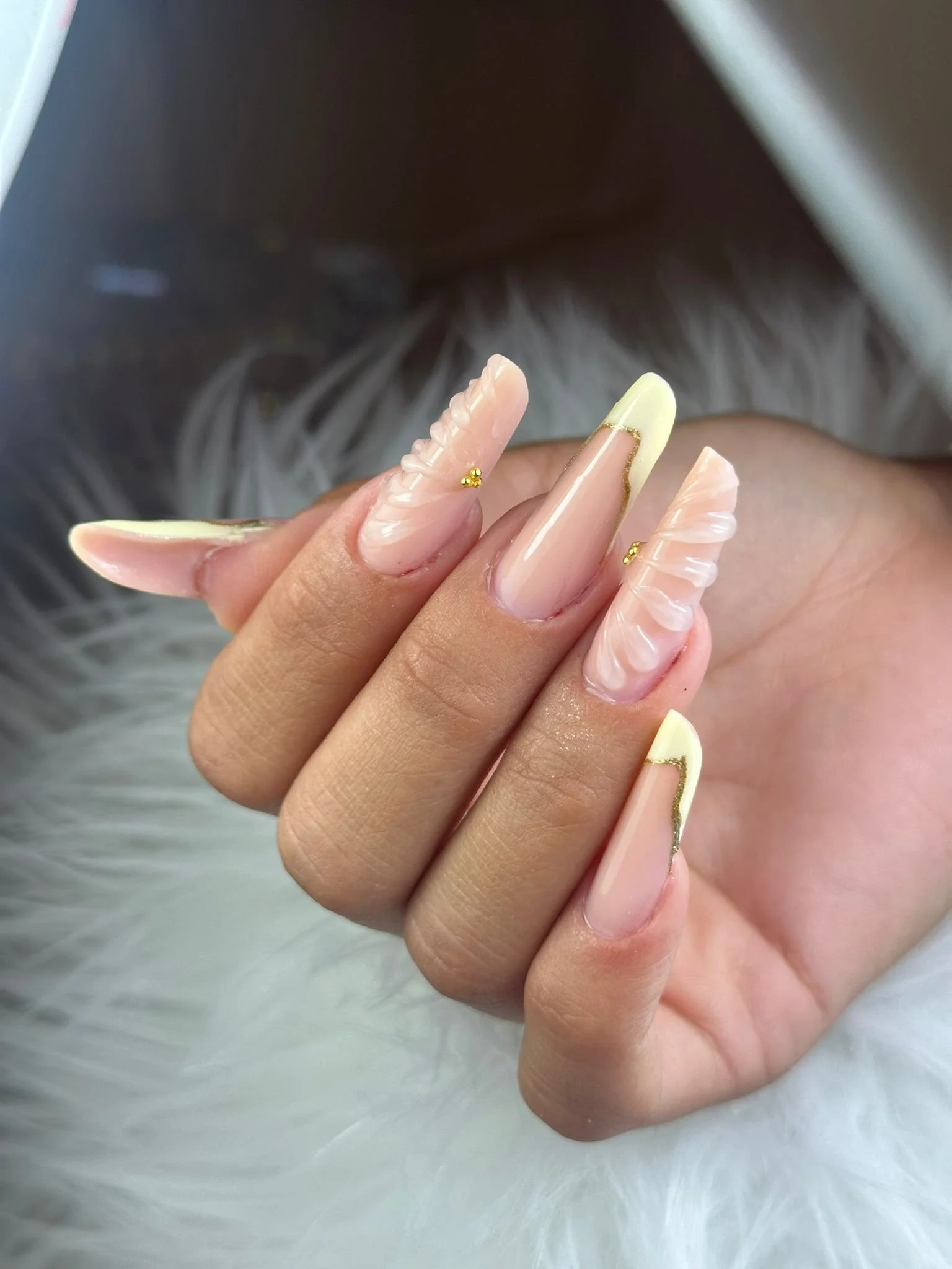 Unghie curate con design nude con dettagli dorati e molli decorazioni a 3D