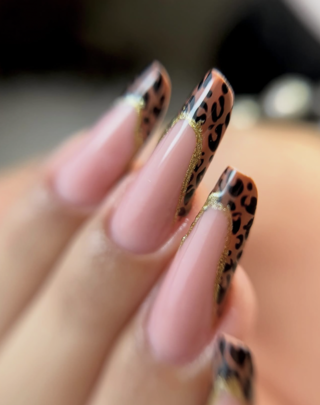 Unghie con design leopardato e dettagli dorati.