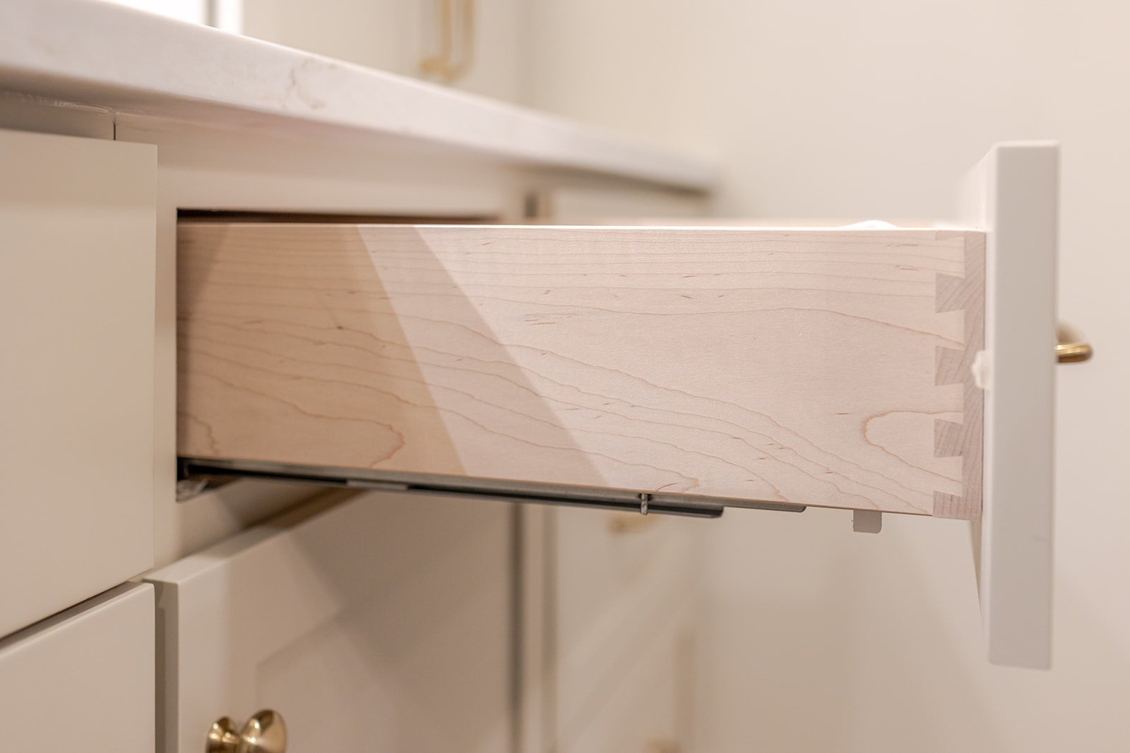 Partially extended wooden drawer in a cream-colored cabinet.
