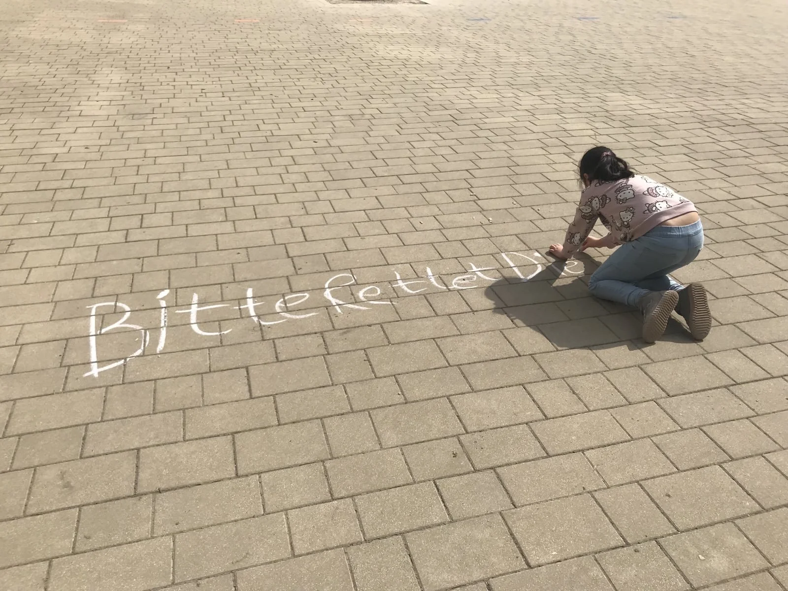 Eine Schülerin schreibt Ihren Mitschüler*innen eine Nachricht auf den Schulhof - WandelWerkstattWelt