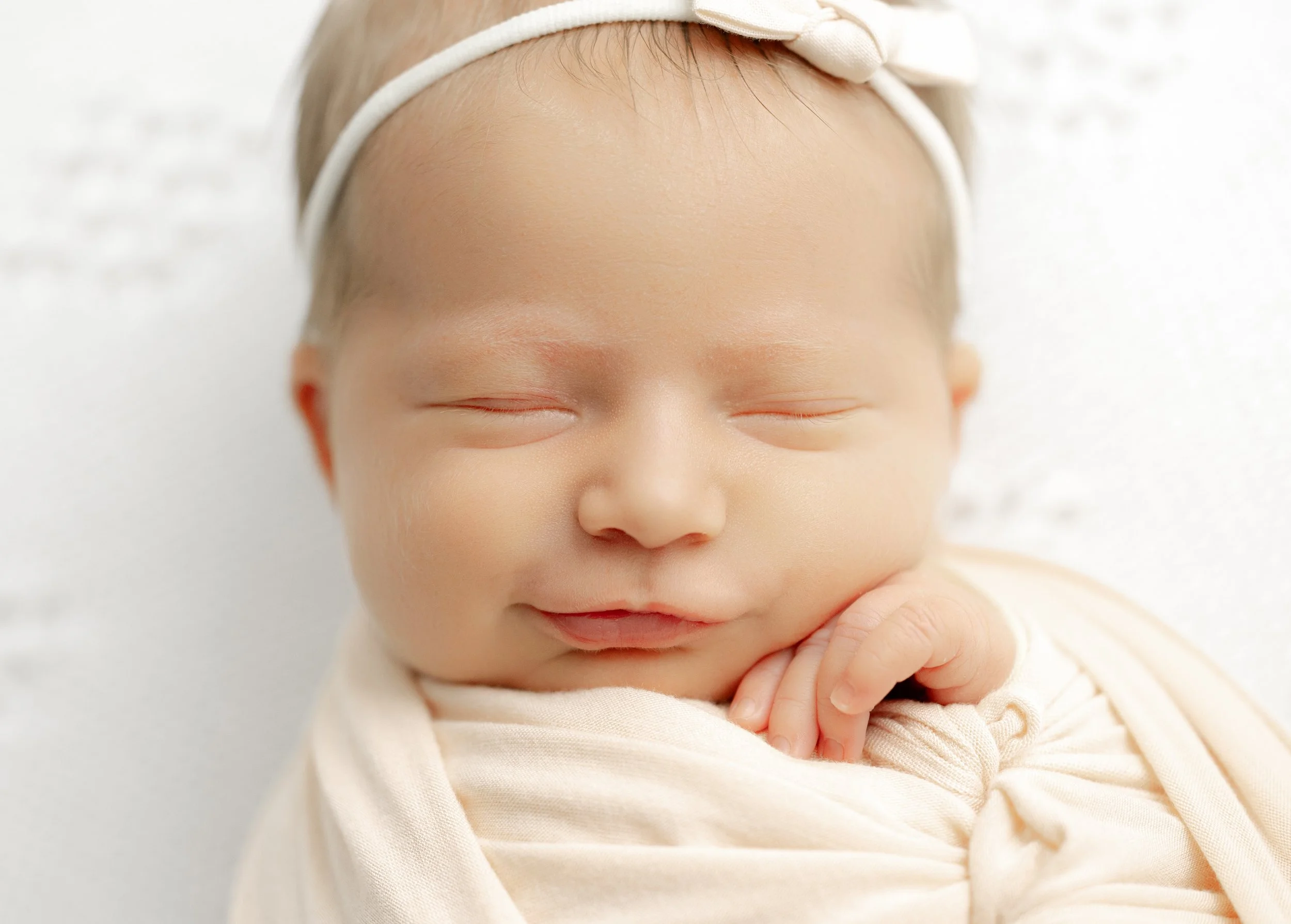 Newborn baby squeezing his eyes and rubbing his fists in his face while stretching.
