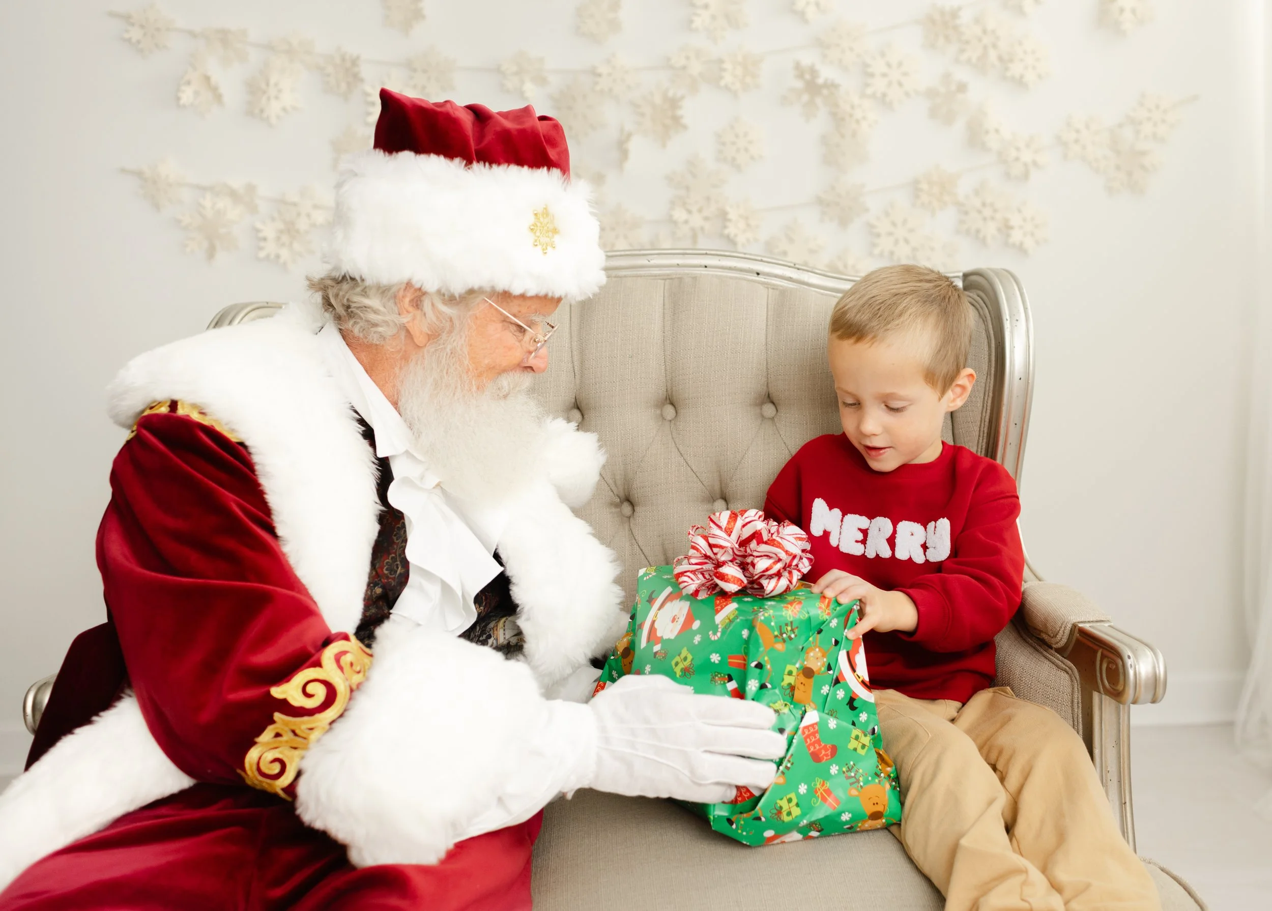 Santa presenting a wrapped gift to a child during the Lynchburg Santa Experience