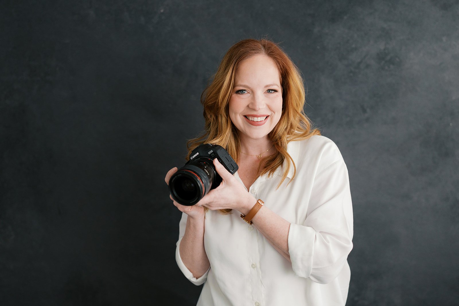 Liz Cook, maternity, newborn, and family photographer serving Lynchburg Virginia and the surrounding Central Virginia area holding a camera.