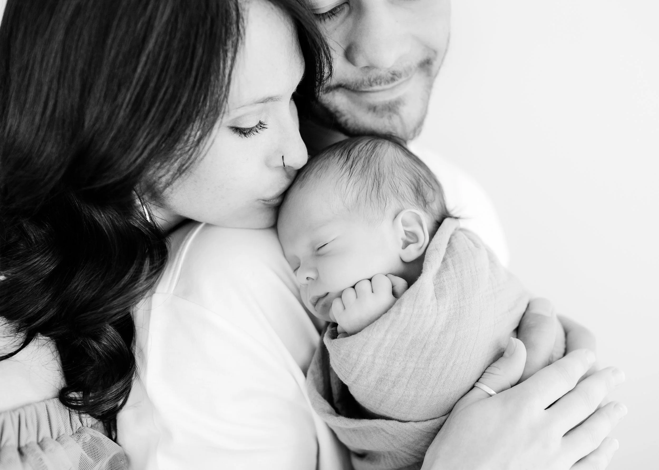 Parents holding and kissing their newborn baby during a newborn photography session by Lynchburg photographer Liz Cook.
