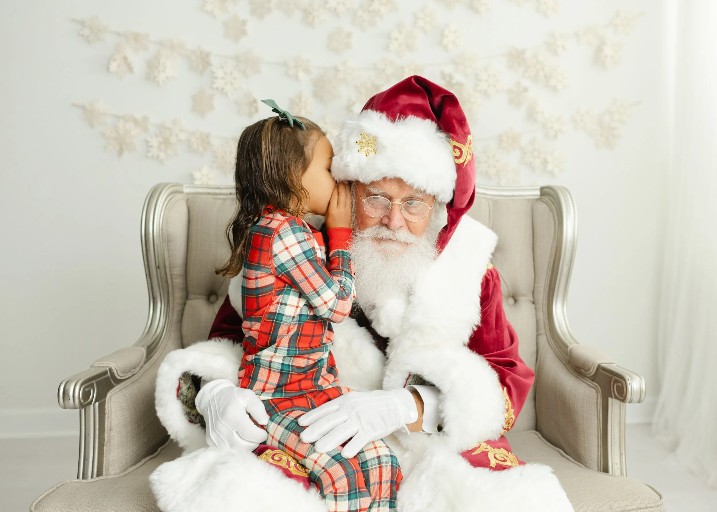 Young girl whispering her Christmas wishes to Santa Charlie during a personalized visit