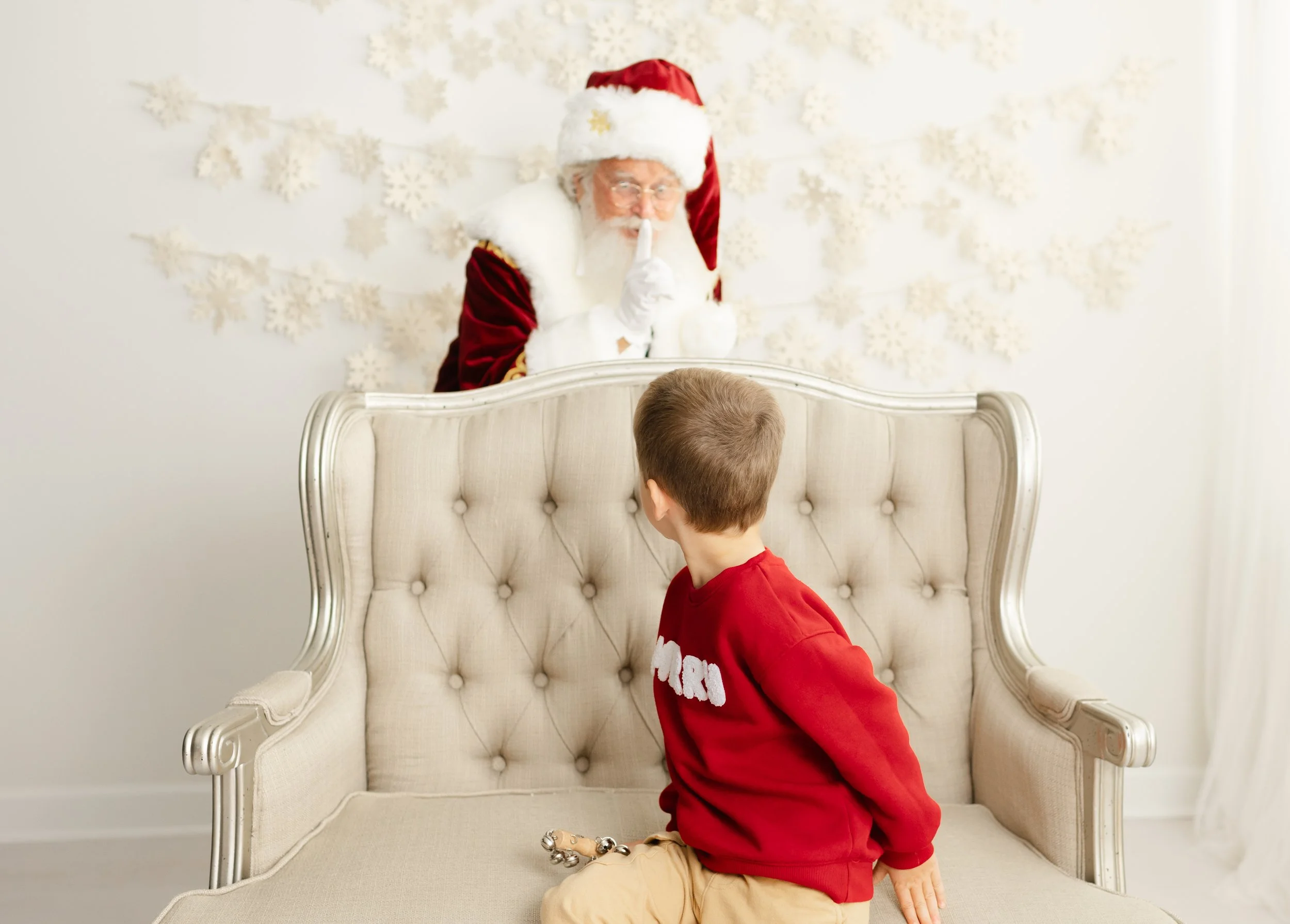 Santa quietly peeking over the settee as a child turns to see him during a gentle Santa visit