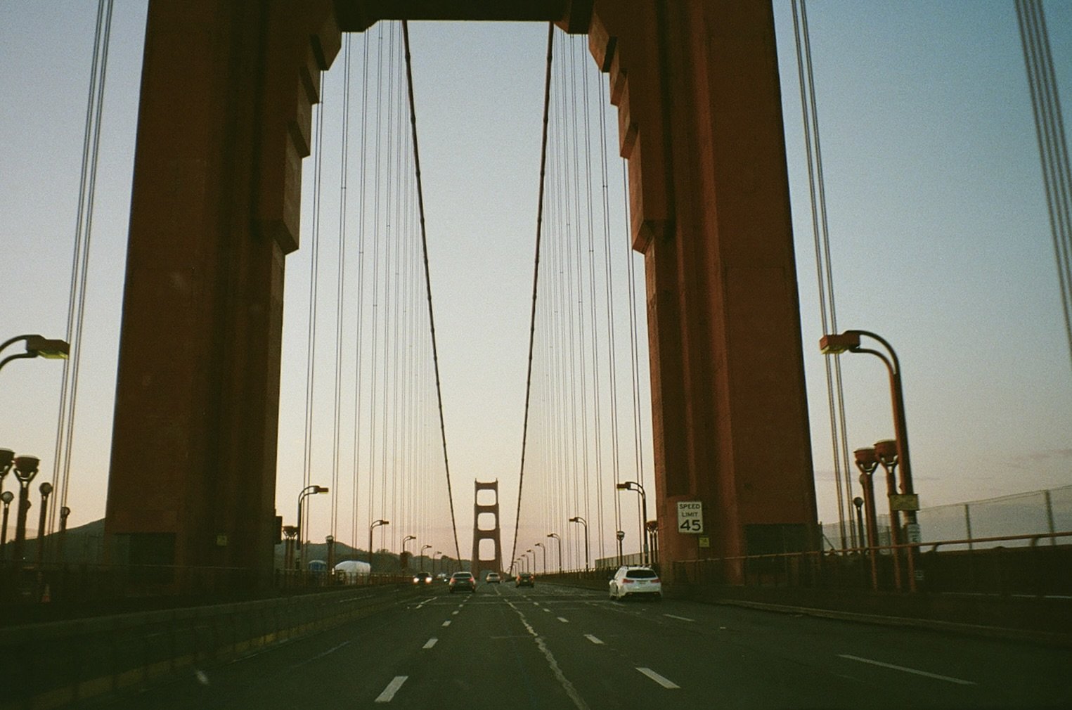 View of the Golden Gate Bridge in San Francisco, California, with cars driving on the road and a clear sky in the background.