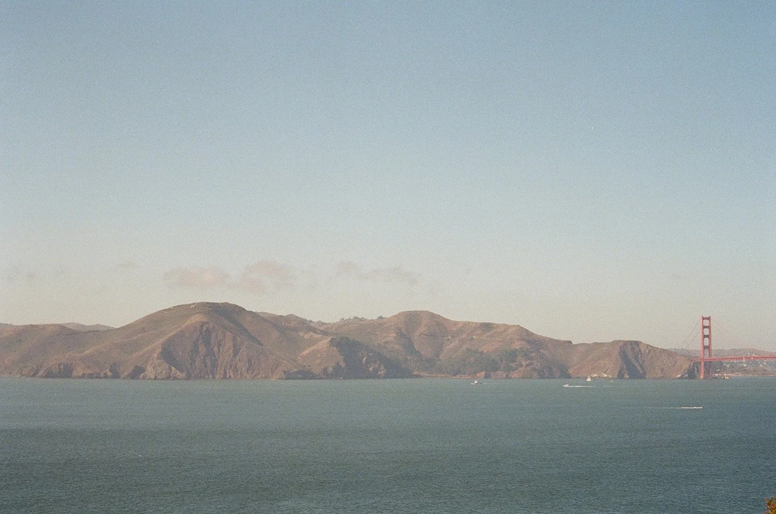 View of the San Francisco Bay with hills in the background and the Golden Gate Bridge partially visible on the right side.