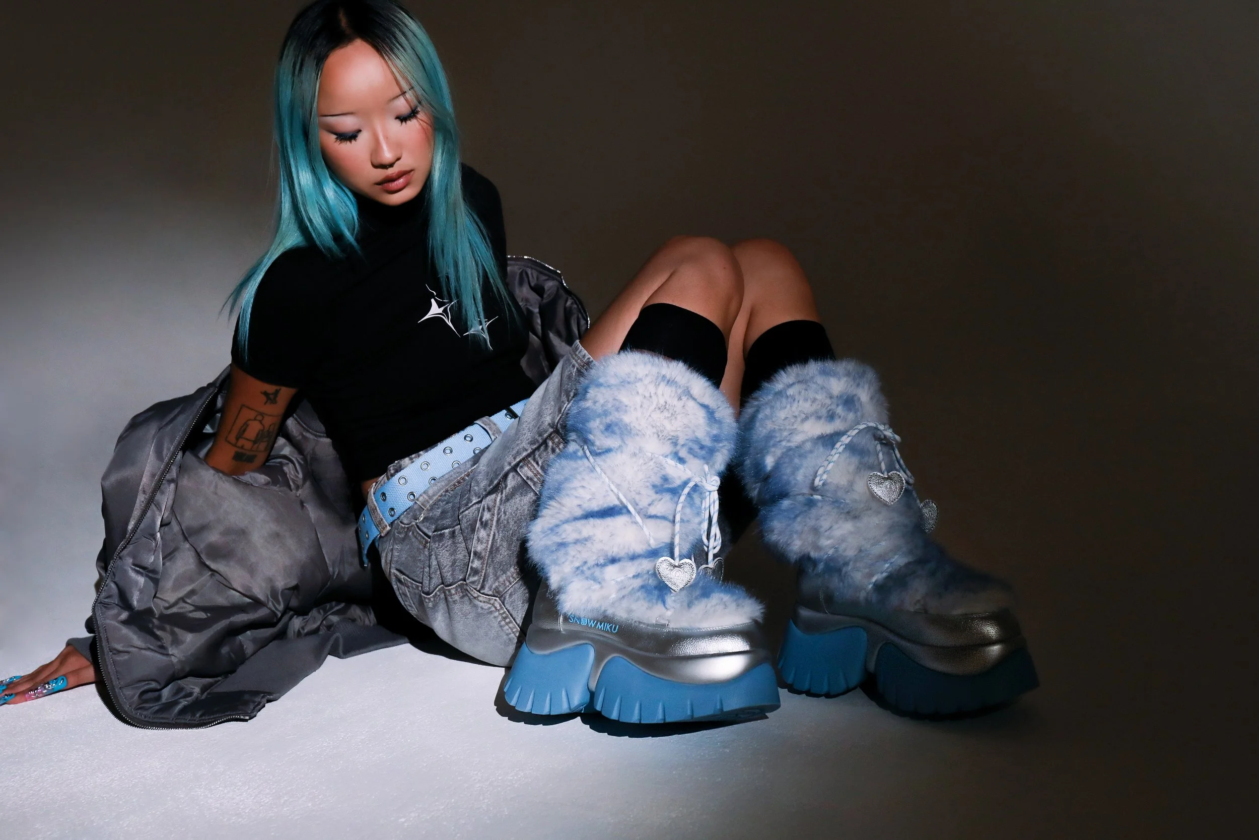 Hatsune Miku x KOI campaign imagery featuring faux-fur snow boots, cyber-pop inspired styling and cool-toned editorial lighting within a dark studio environment.