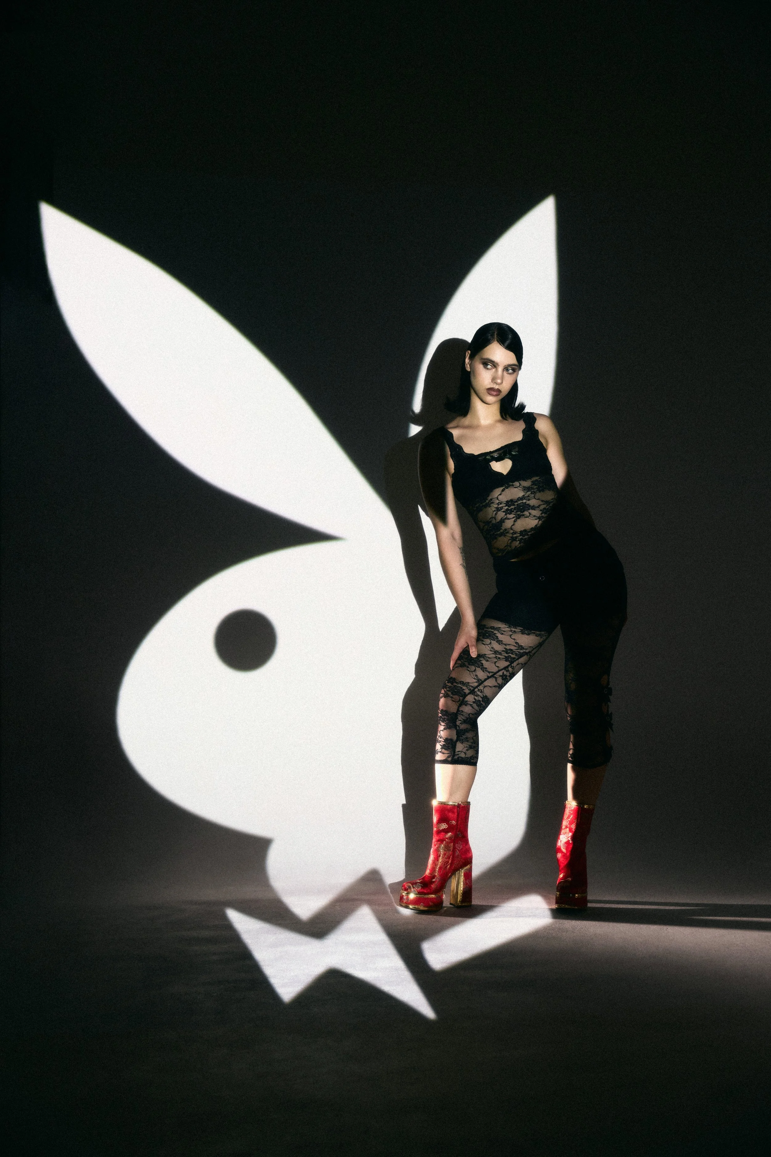 Campaign imagery for Playboy x KOI blending dramatic lighting, oversized Playboy iconography projection and statement footwear styling to create a bold, theatrical visual identity across social and launch content.