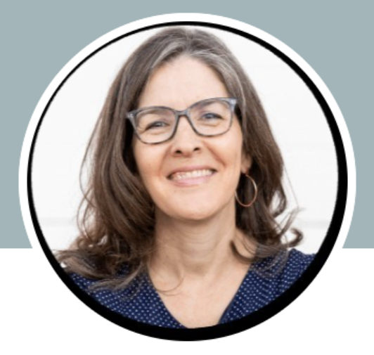 A woman with shoulder-length brown hair, glasses, and hoop earrings smiling, wearing a blue polka-dot top, against a white background.