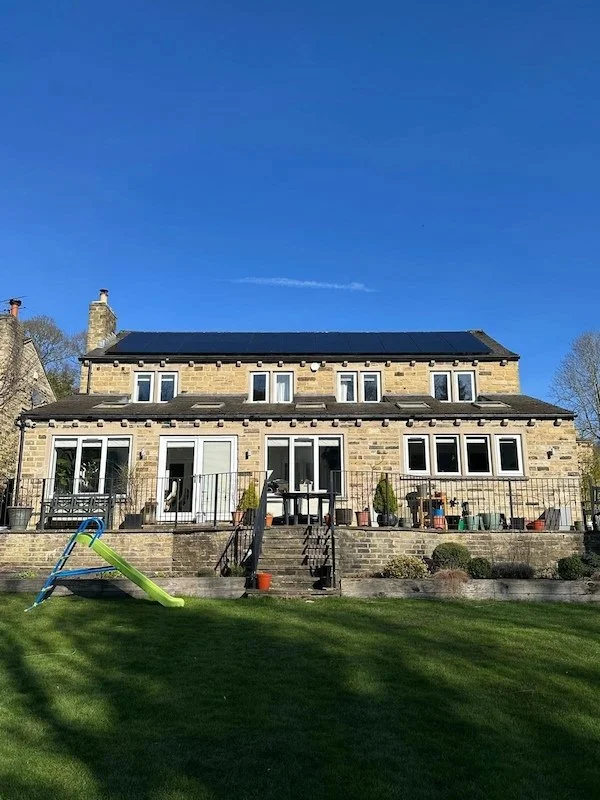 Large stone detached house with solar panels installed on the roof, Wakefield