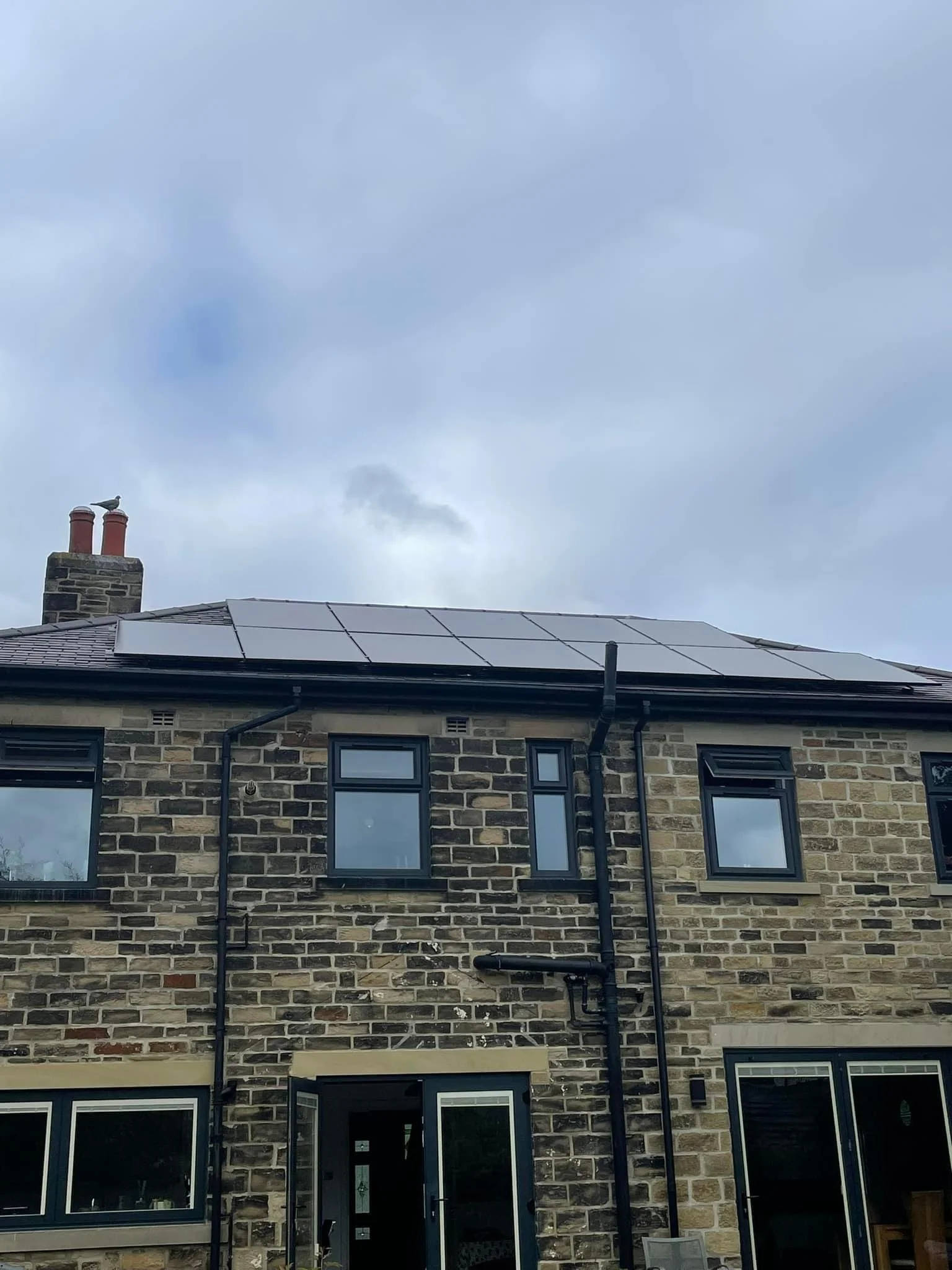 Solar panels installed on the roof of a stone-built terraced house, Bradford