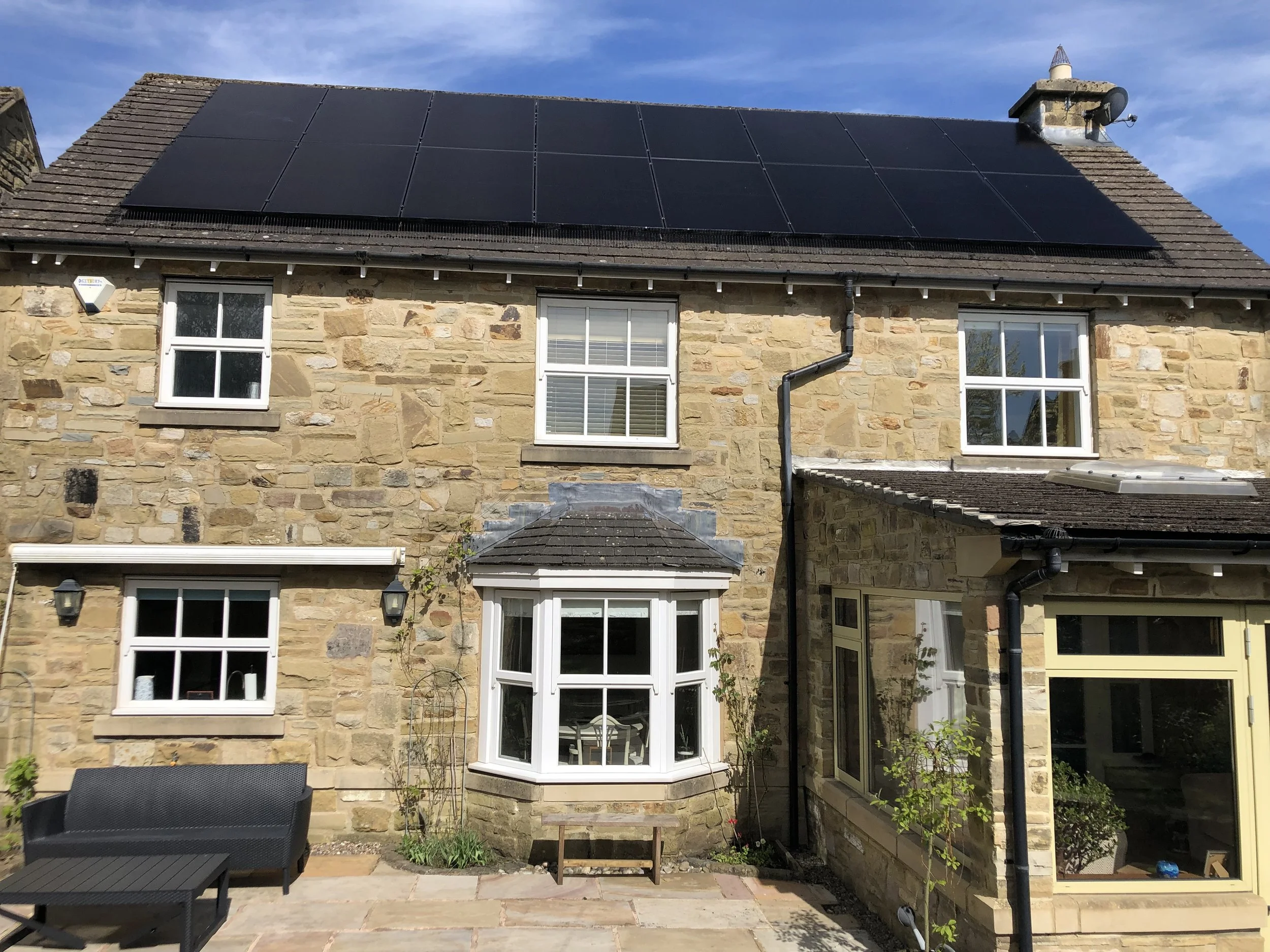 Traditional stone-built home with roof-mounted solar panels generating clean renewable energy and lowering electricity costs.
