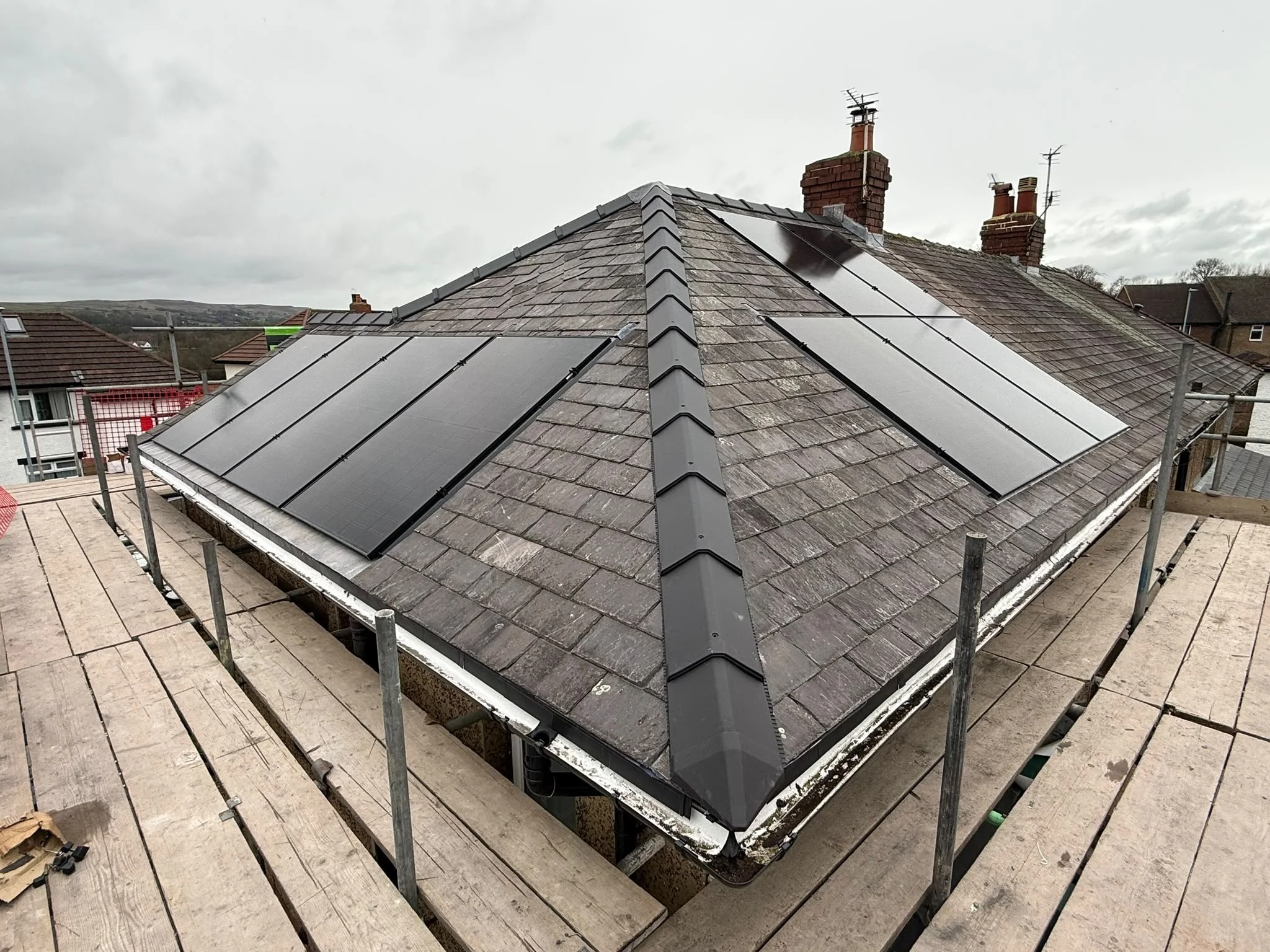 Aerial view of solar panels installed across a pyramid-style roof with chimneys, Bradford
