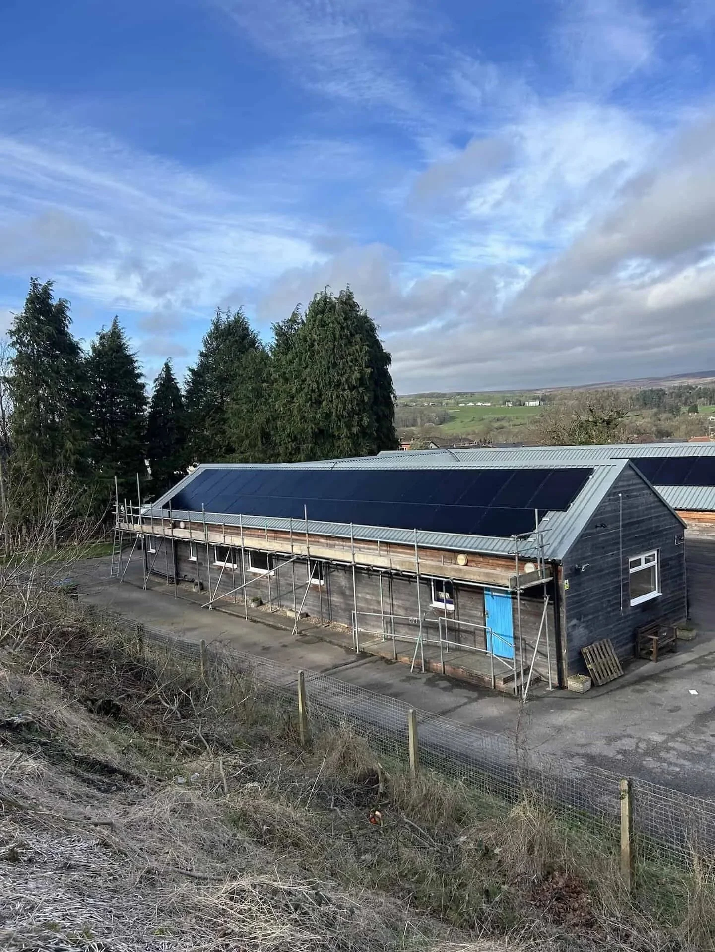 Solar panel installation completed on the roof of Ben Rhydding Scout & Guide Group headquarters, with scaffolding in place during the final stages of the project.