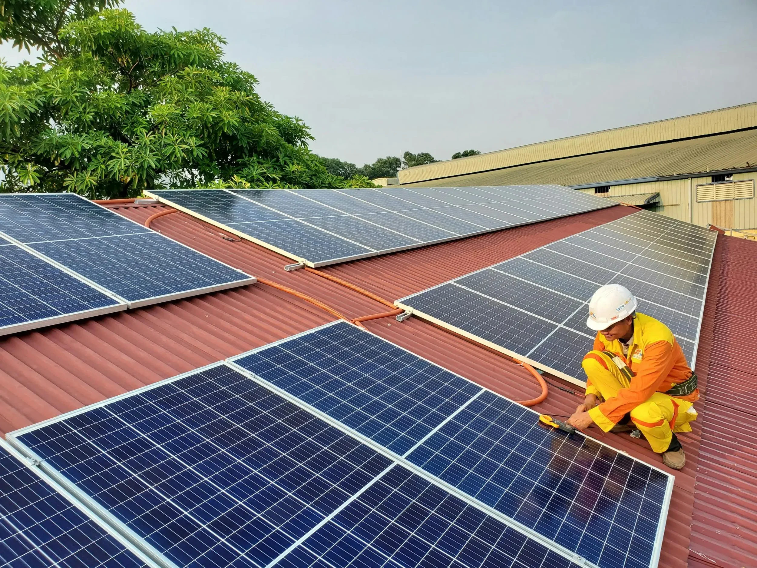 Solar panel technician inspecting and maintaining rooftop solar panels, illustrating solar panel replacement, upgrades and government funding options