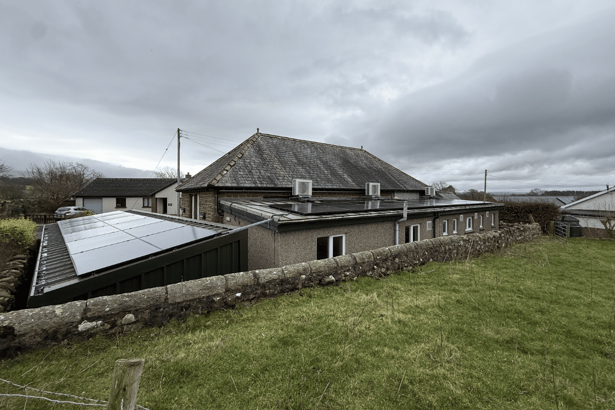 A house with solar panels on the roof and a grassy yard in the foreground.