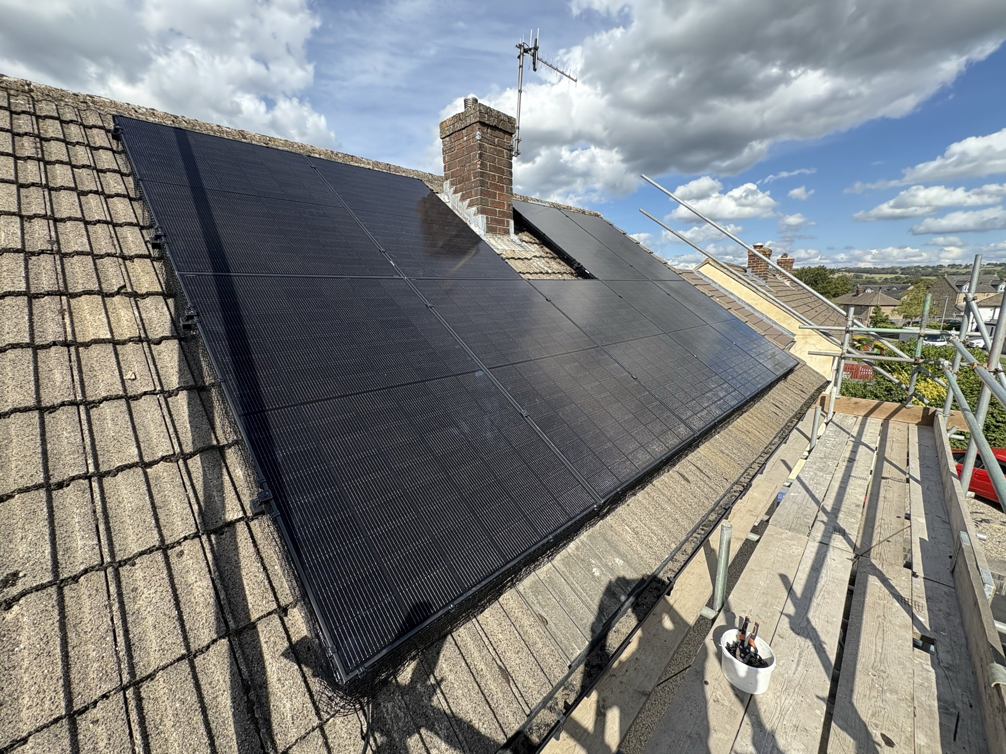 Solar panel array installed on a roof with chimney, overlooking Bradford and Keighley