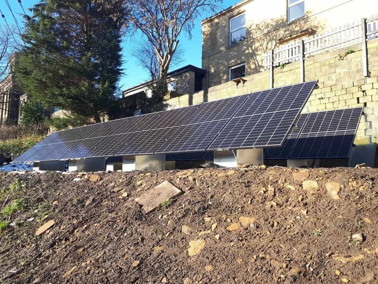 Completed ground-mounted solar panel system installed on a sloped residential garden, providing renewable energy generation with an optimally angled solar array.