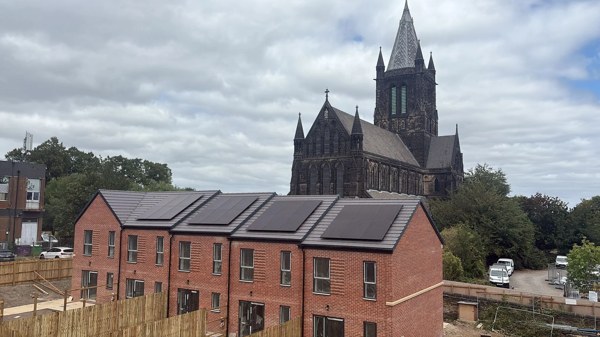 Residential housing development with rooftop solar panels installed across multiple new-build homes.