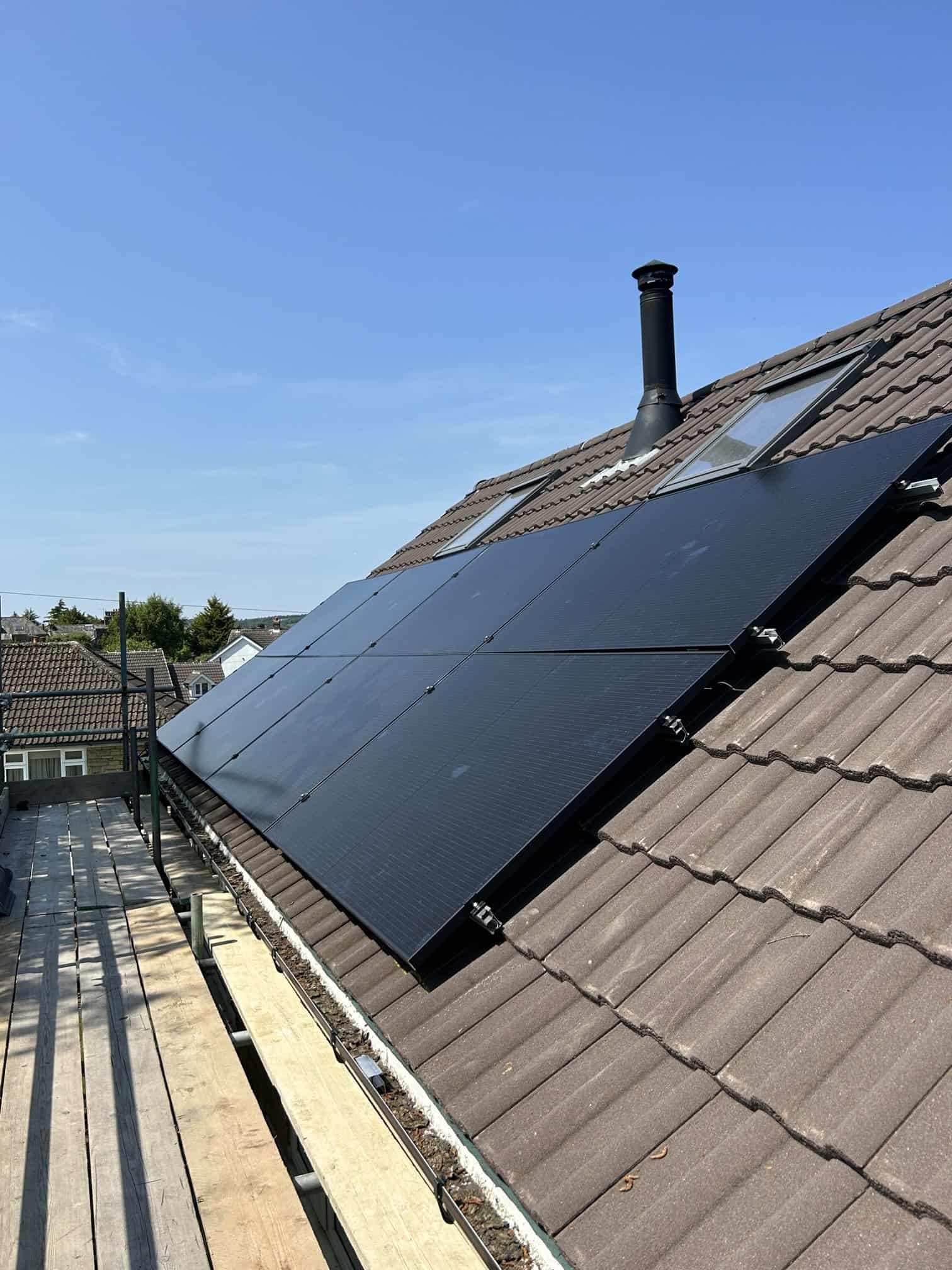 Close-up of solar panels installed on a roof with chimney, showing panel detail