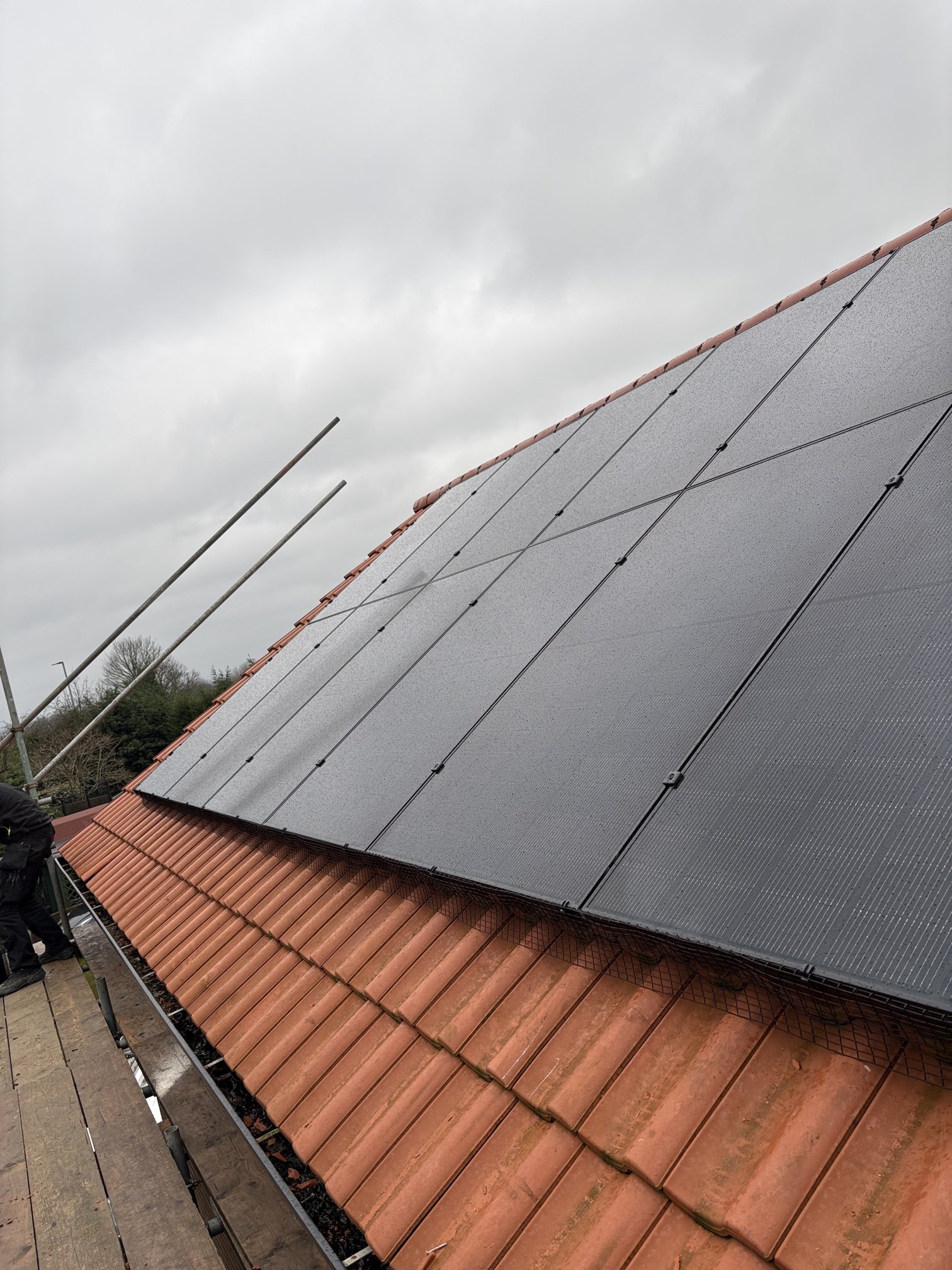 lose-up of solar panels installed on a roof next to a red-tiled roof section