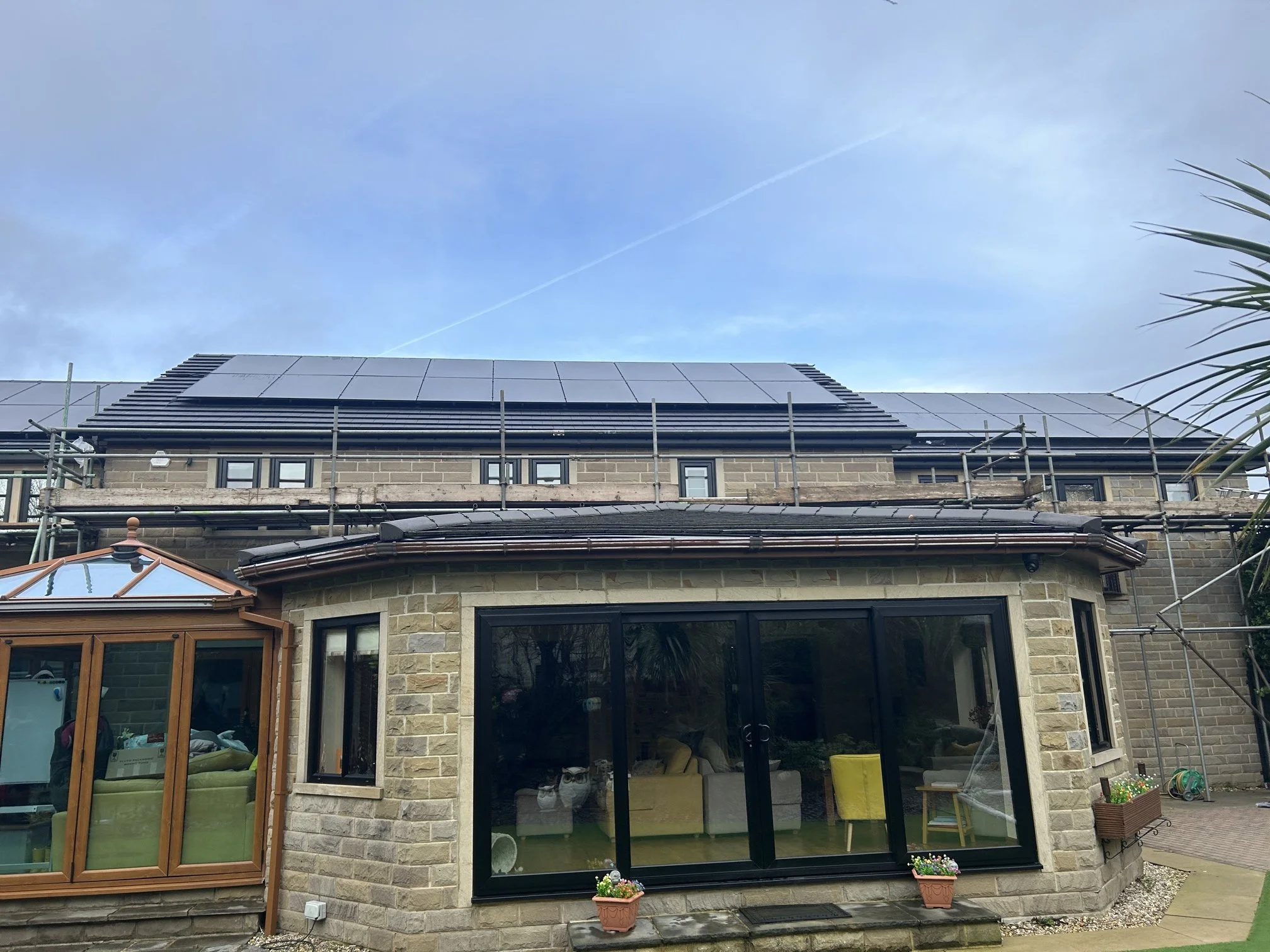 Stone detached house with solar panels installed on the roof and a glass extension, Wakefield