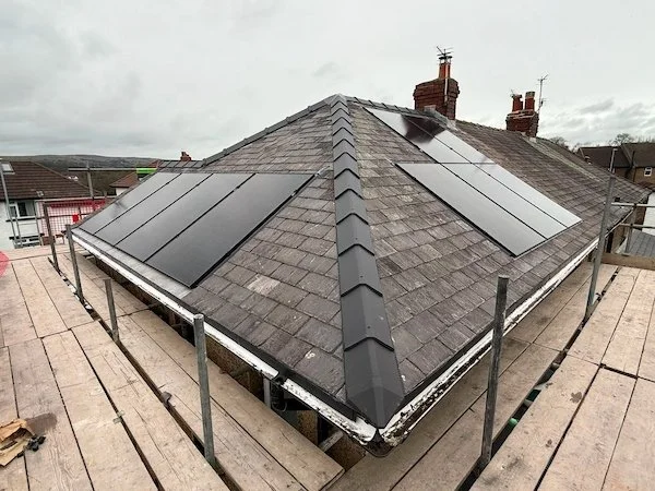 Aerial view of solar panels installed across a pyramid-style roof with chimneys, Bradford