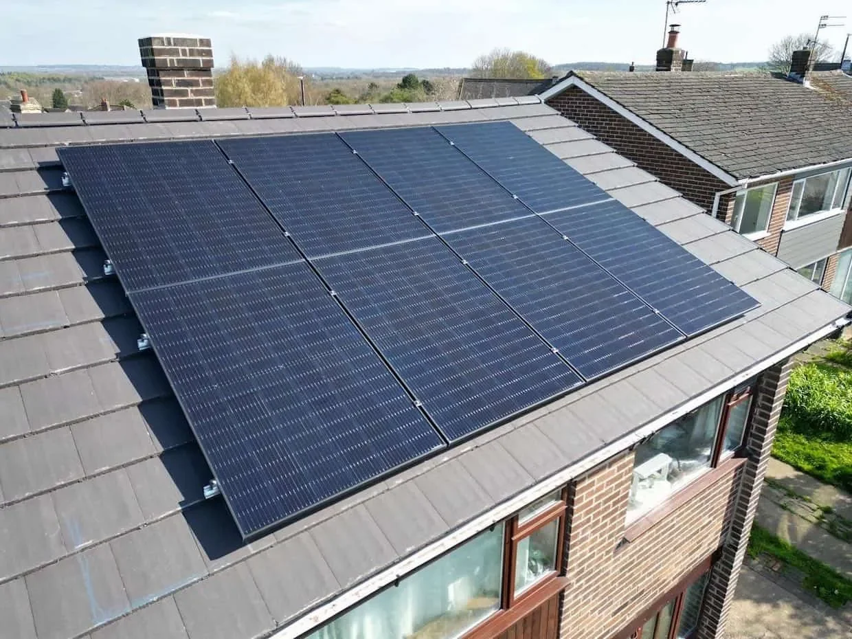 Engineers installing rooftop solar panels on a UK home as part of a residential solar energy system.